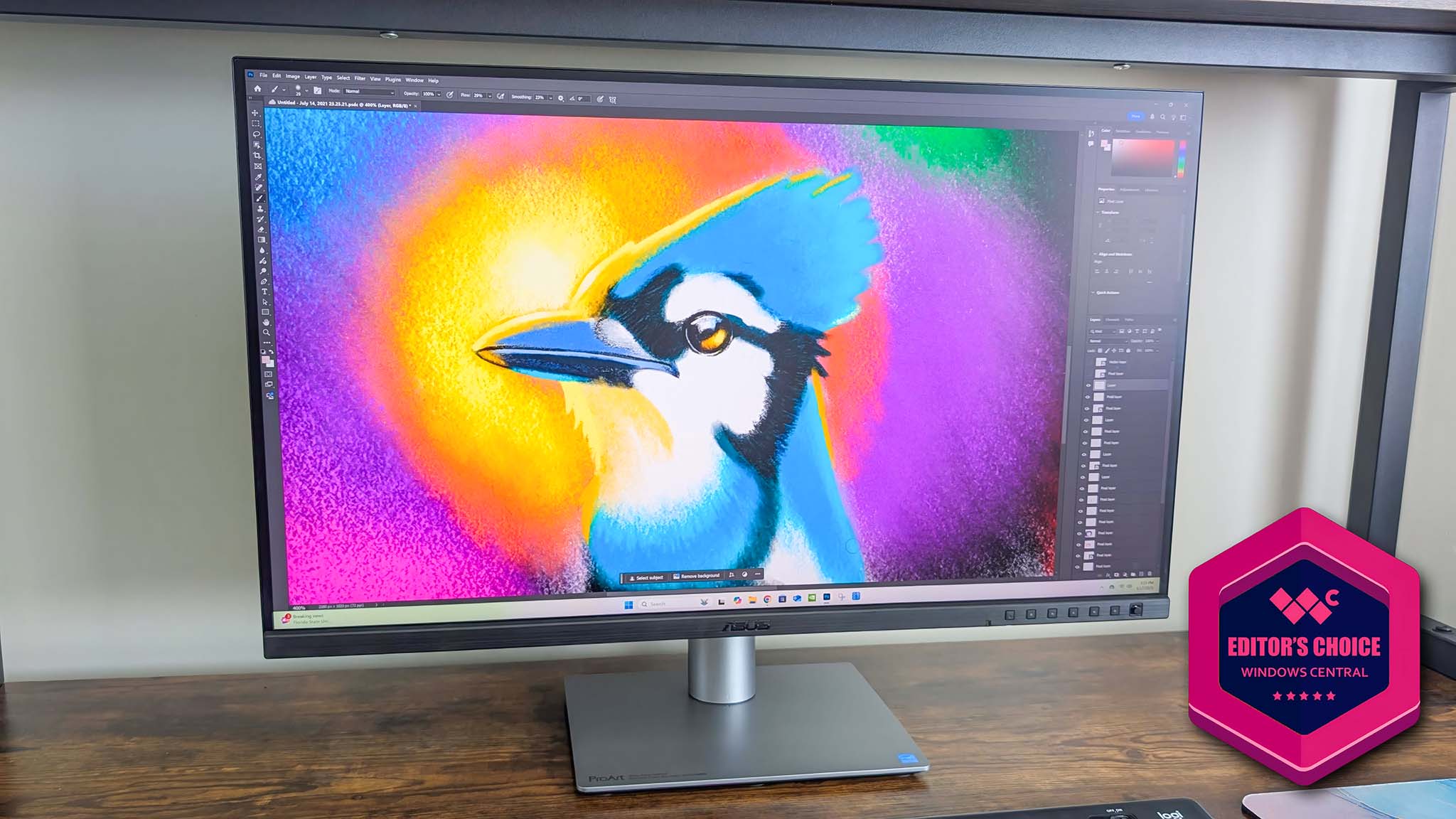ASUS ProArt PA27JCV monitor on a desk and displaying Adobe Photoshop with a vibrant image of a bluejay. An Editor&#039;s Choice award is in the bottom right of the image.