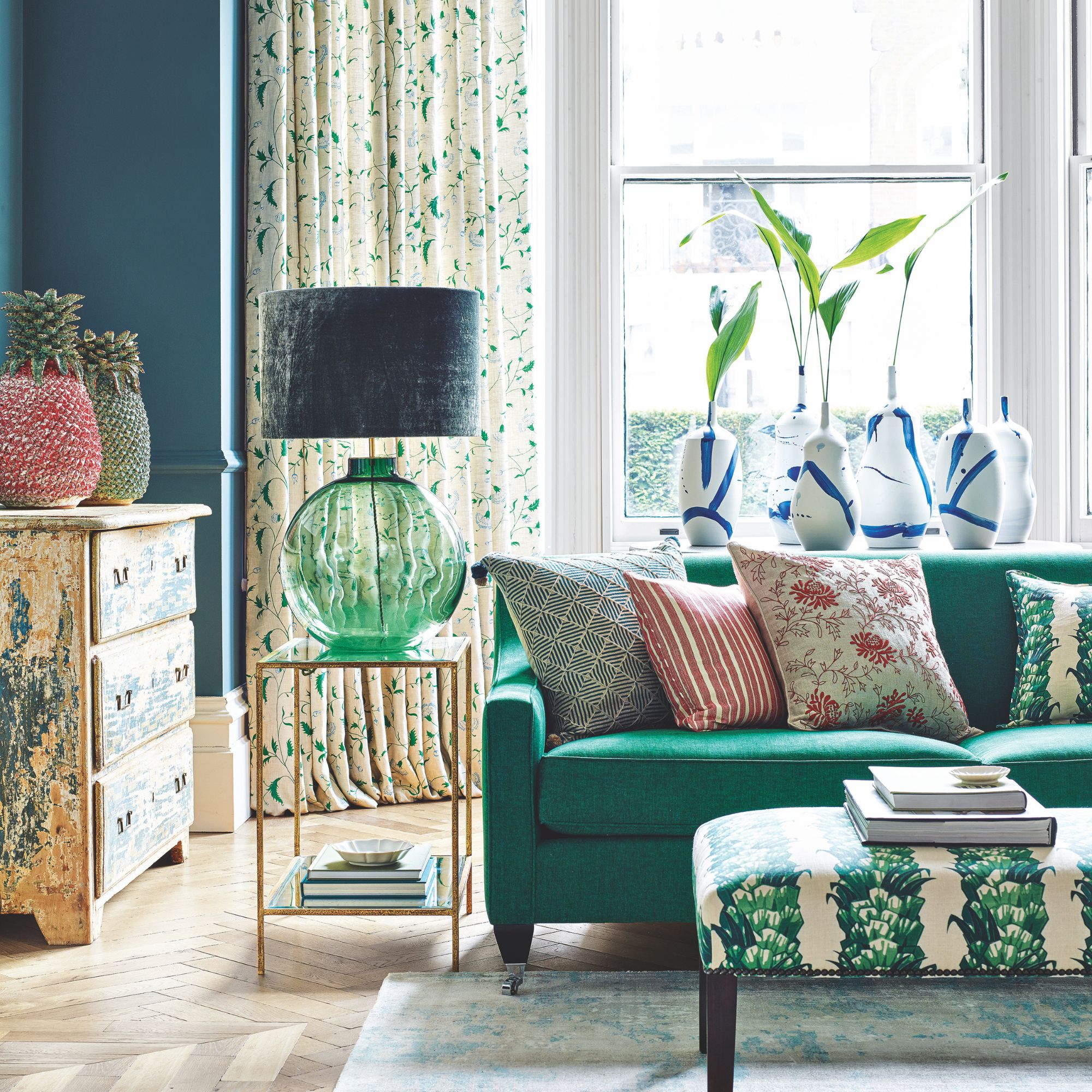 A living room with botanical accents throughout on curtains, cushions and footstall
