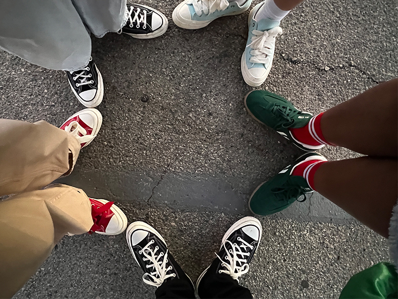 Five people wearing Converse shoes while forming a star with their feet.