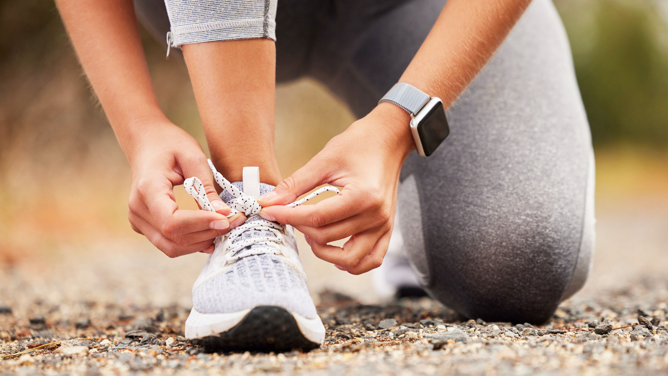a photo of a woman lacing up her running shoe