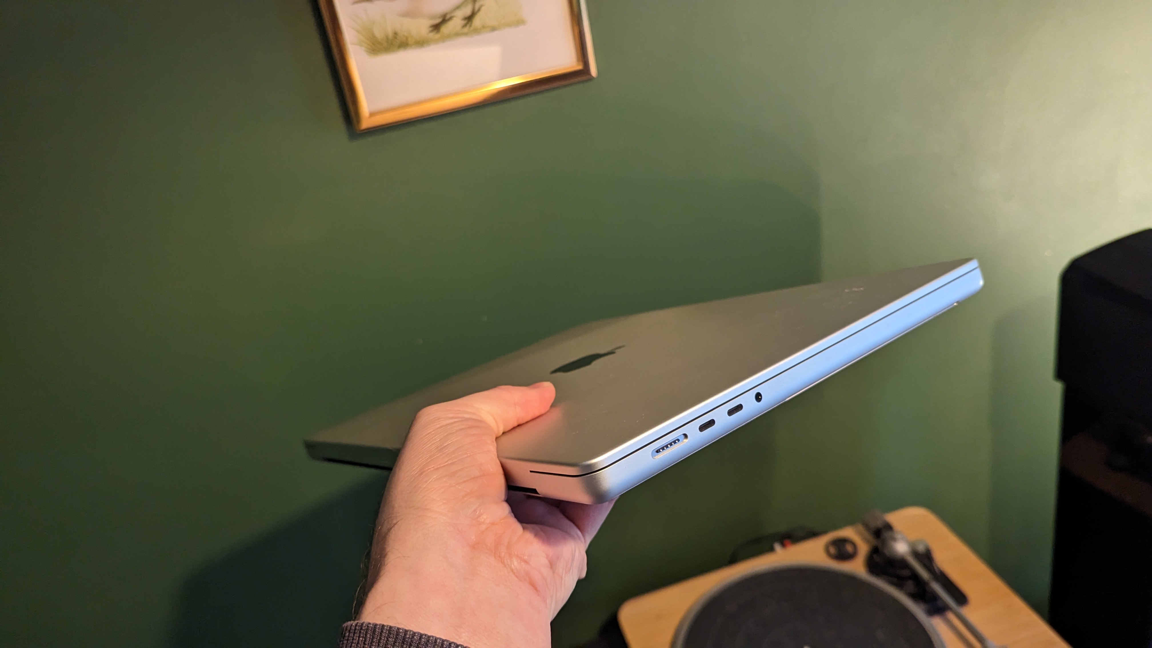 MacBook Pro 16-inch (2023) on wooden desk with green background