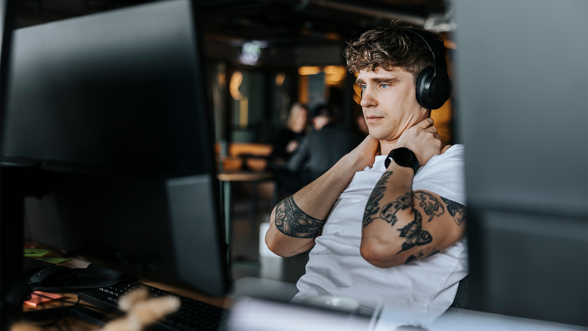 Male software developer looking stressed at a desktop computer in open plan office space over vulnerable MCP servers and software security flaws.