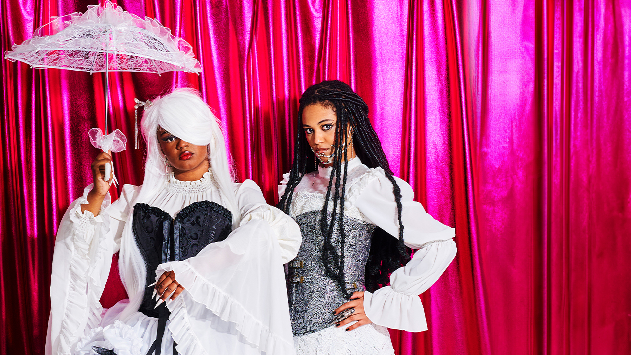 Alt Blk Era dressed in white dresses in front of a pink curtain