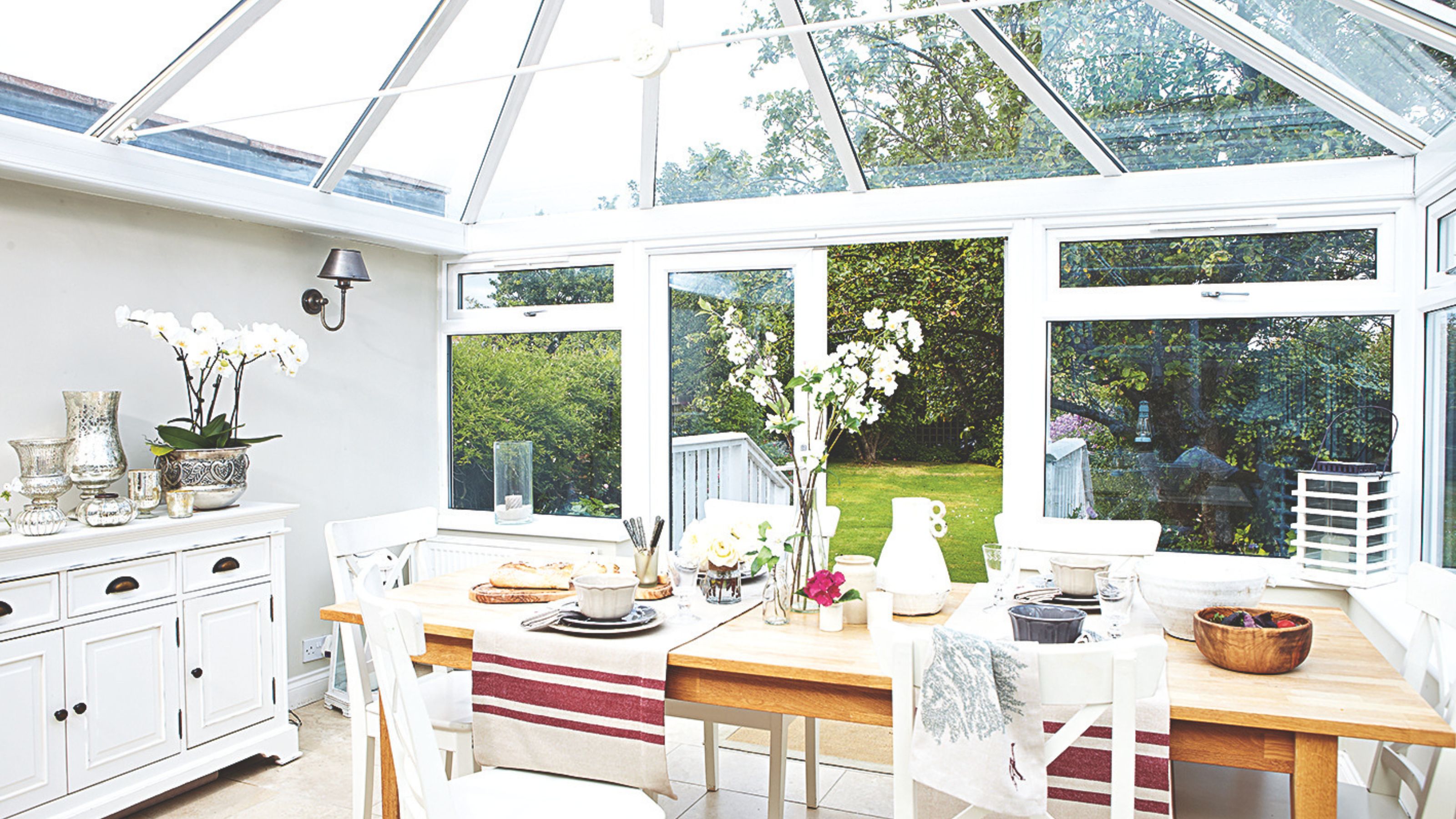 Conservatory with dining table and chairs, with views of a spacious garden