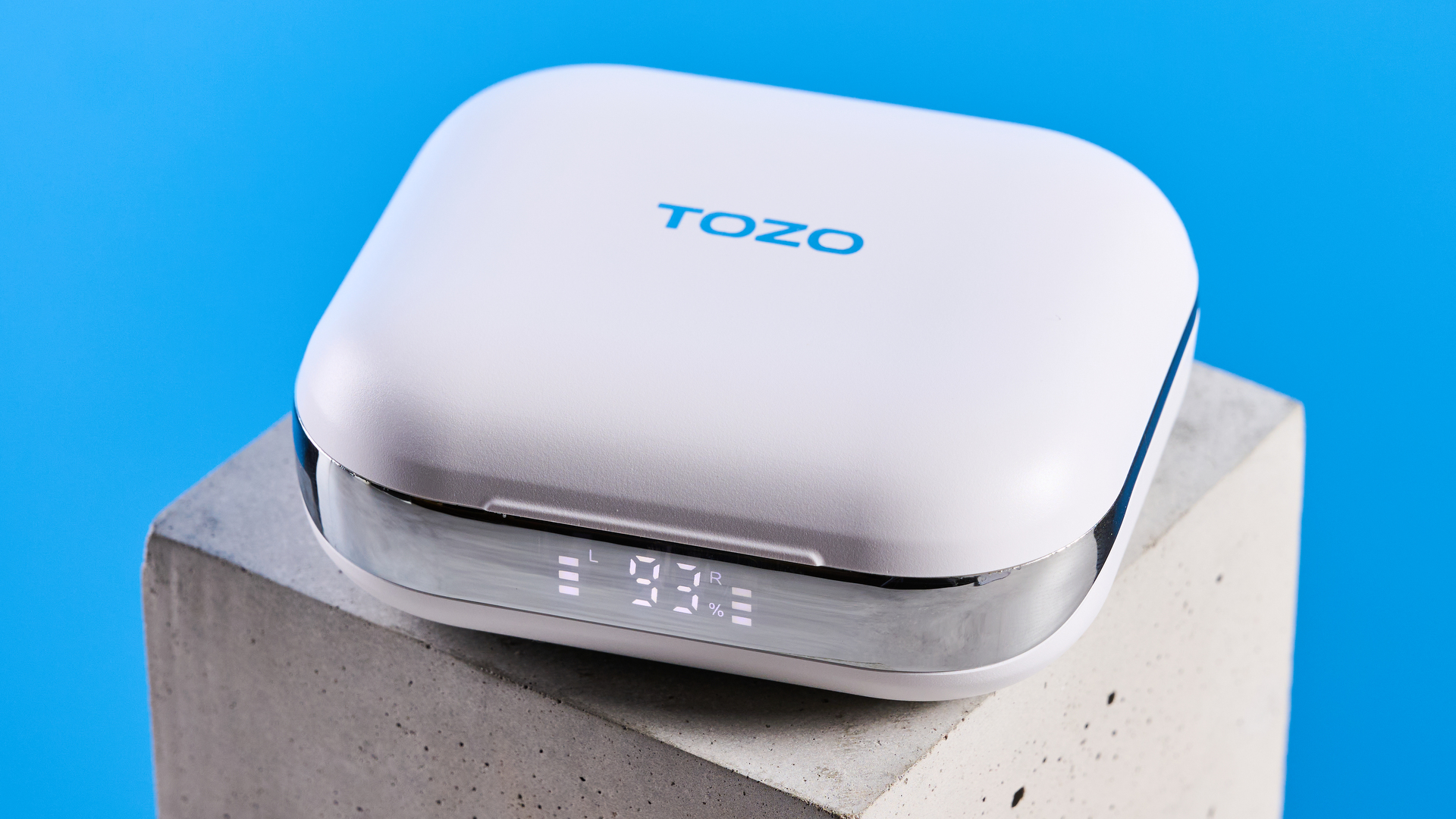 Tozo OpenEgo open-ear earbuds photographed in front of a blue background.