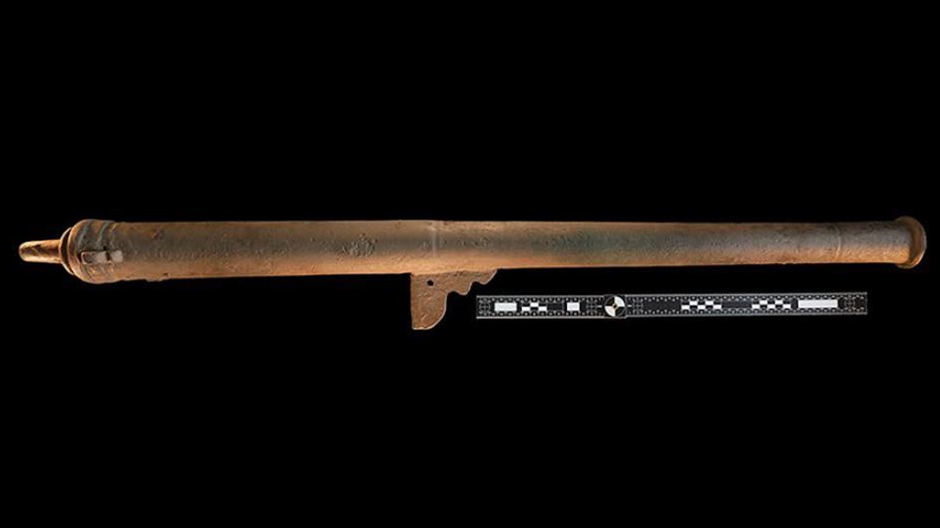 a bronze cannon against a black background