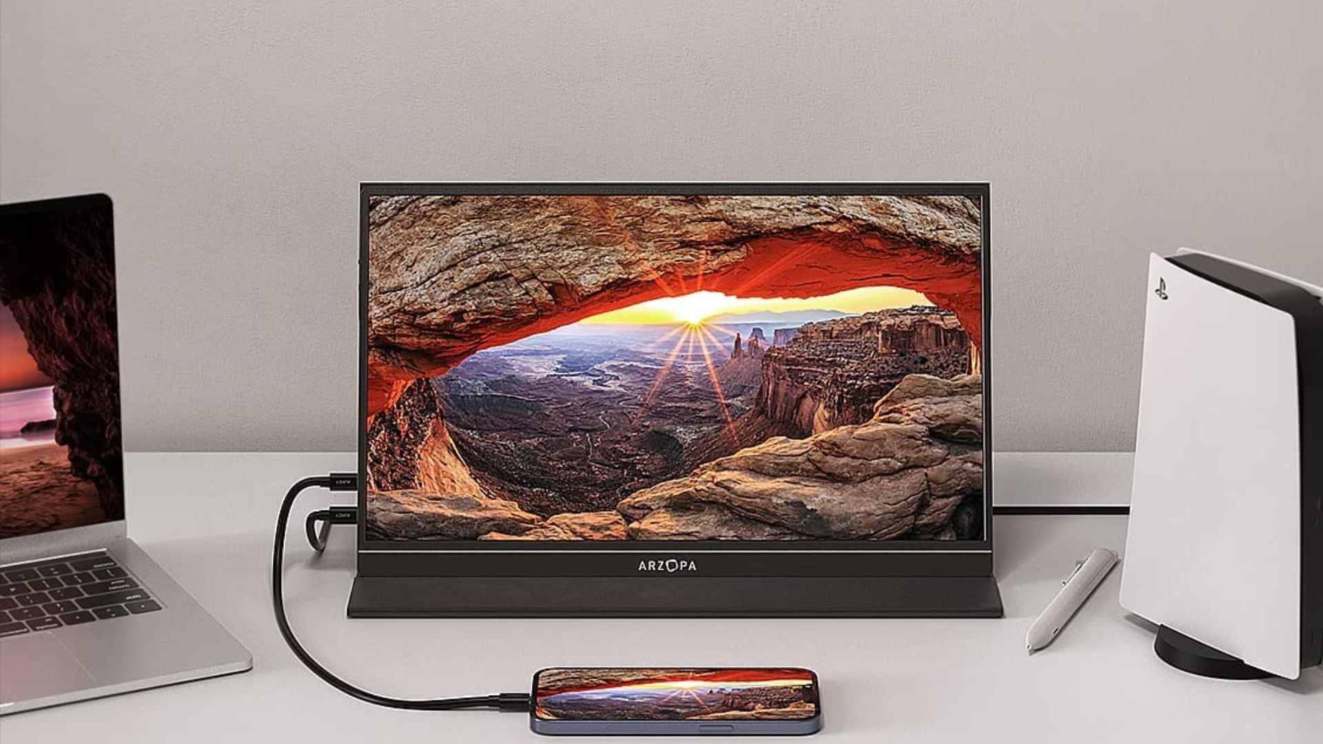 The Arzopa portable monitor on a desk next to a PS5 and MacBook.