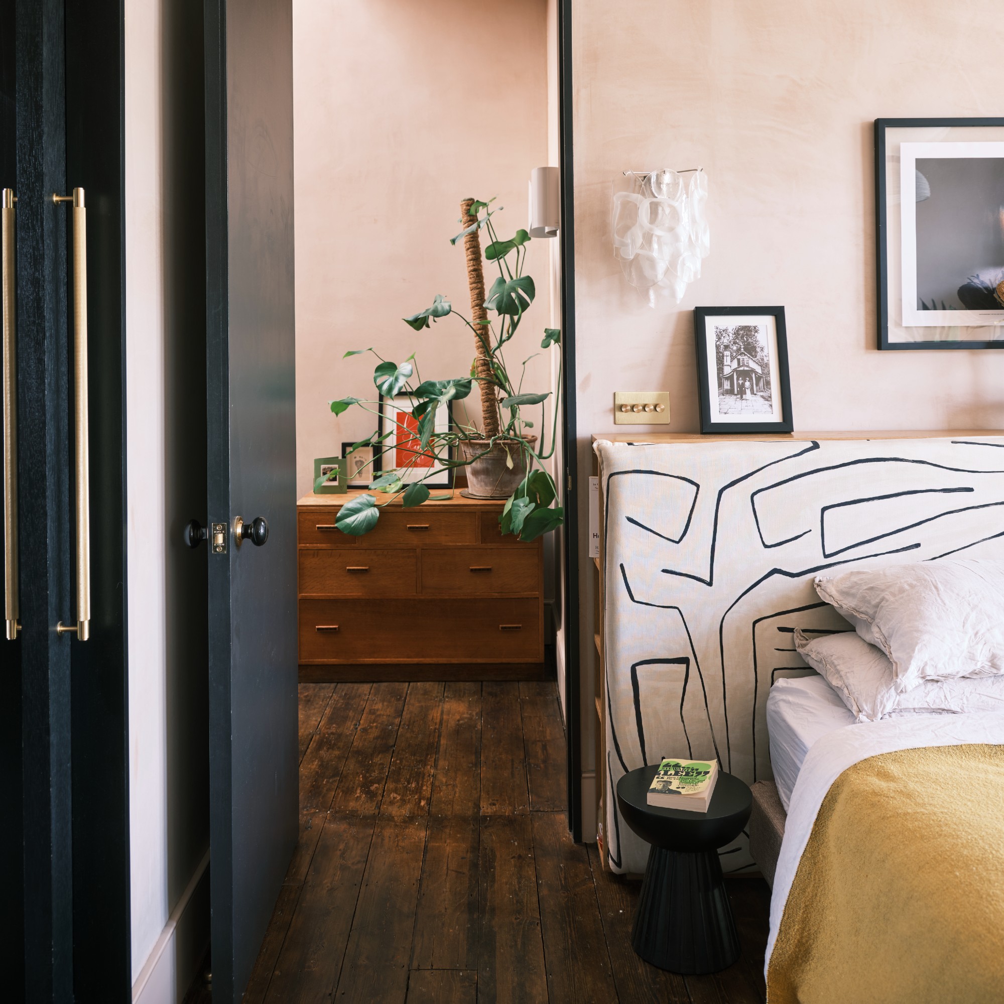 A light pink-painted bedroom with an abstract, statement storage headboard on the bed