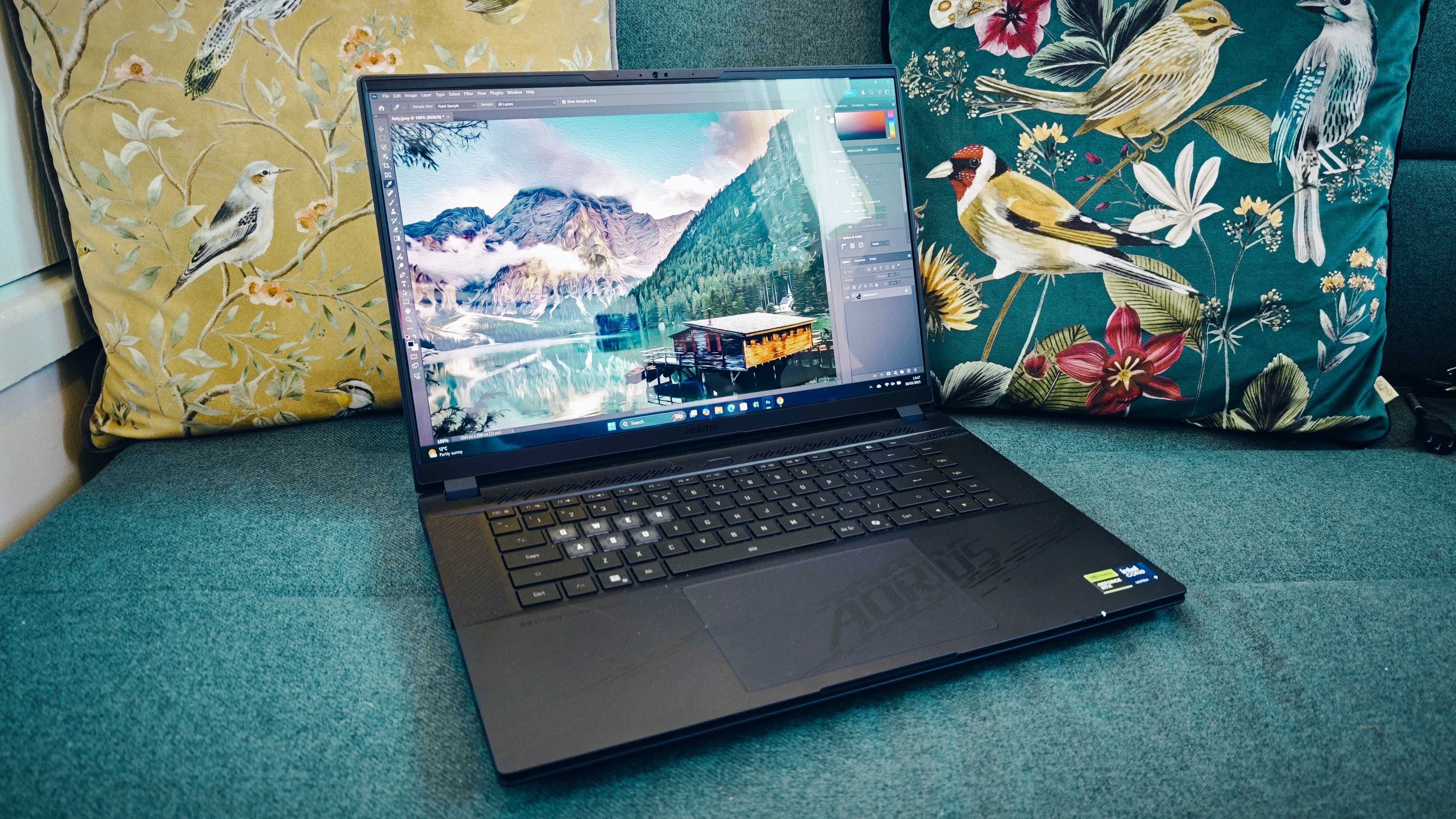 A Gigabyte Aorus Master 16 laptop on a green sofa