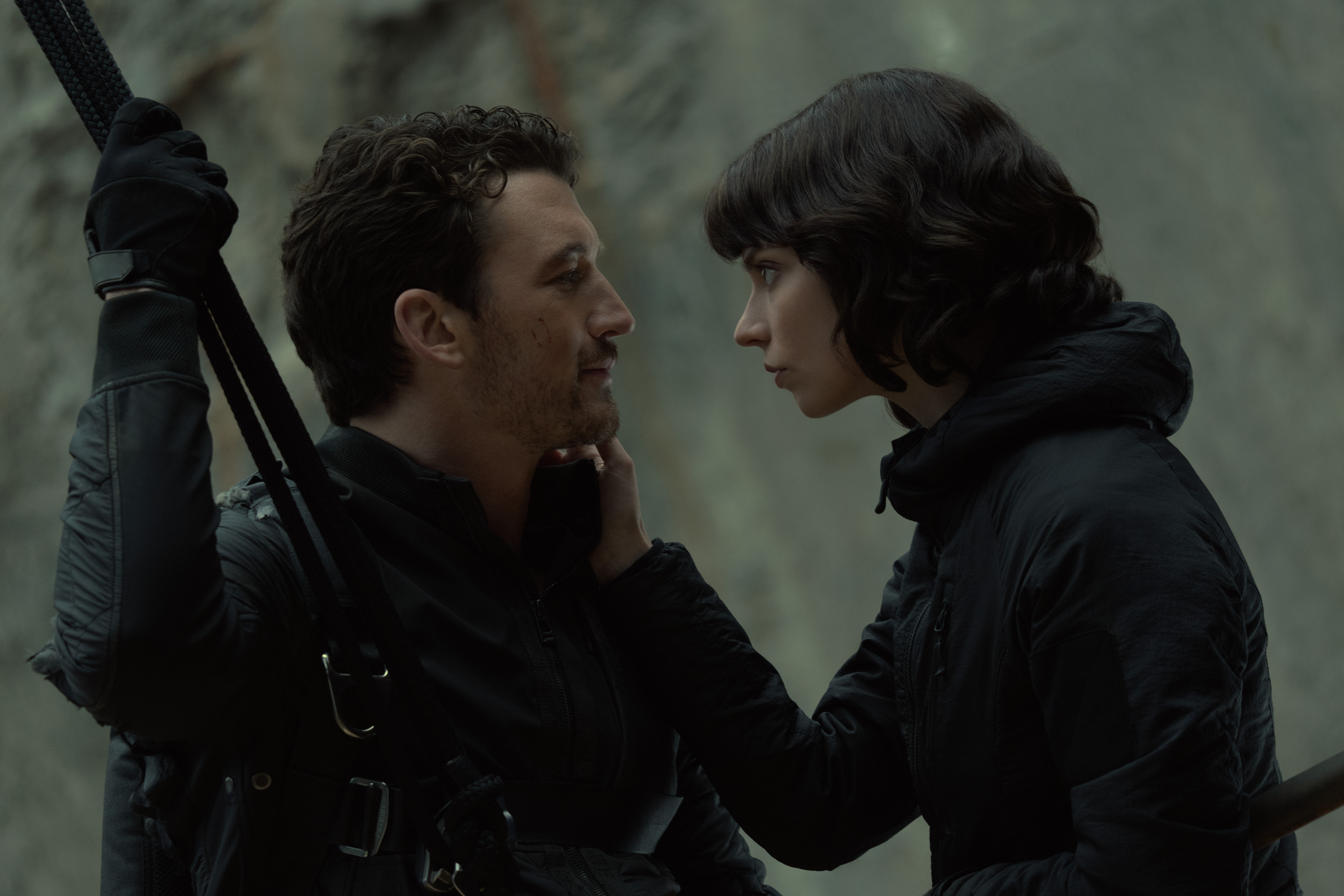 miles teller and anya taylor joy lean into one another while suspended on a cliff in the movie the gorge