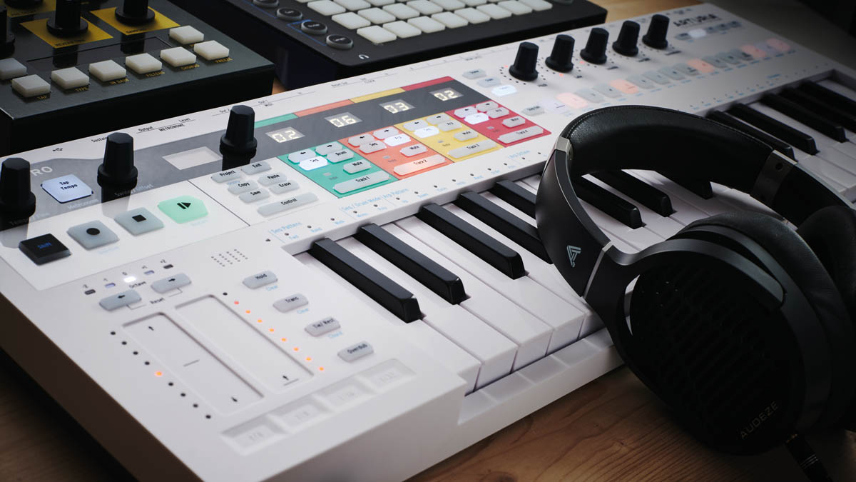 An Arturia KeyStep Pro MIDI keyboard with a pair of headphones lying on it