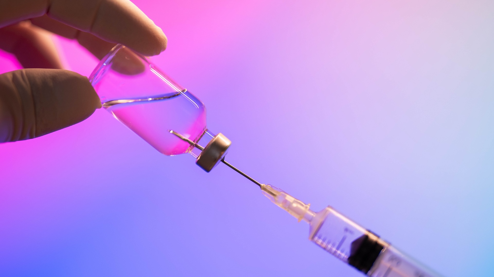 A close-up of a doctor loading a syringe with a dose of a vaccine