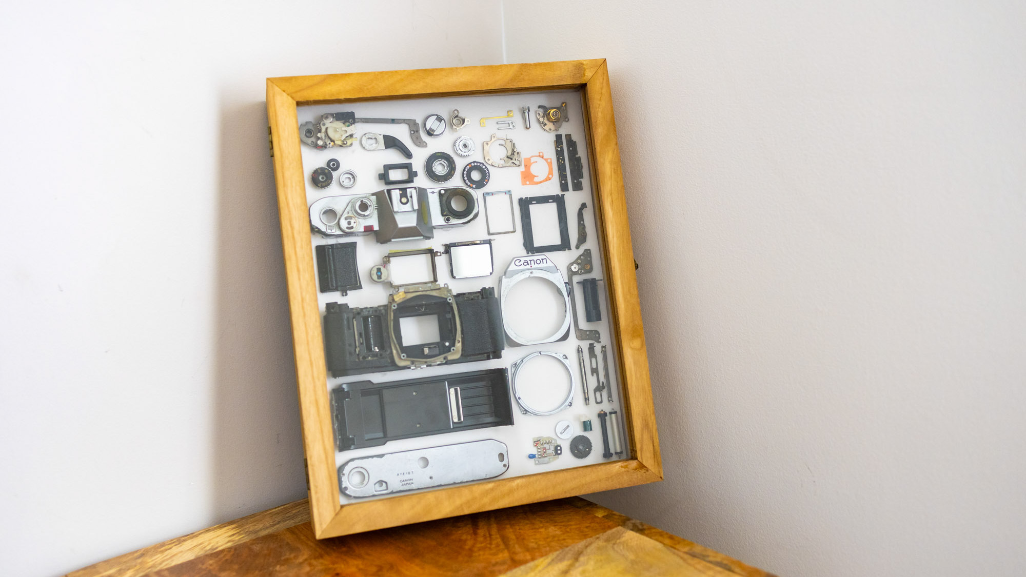 A man taking apart a broken Canon AV-1 film camera to create a new work of art from its pieces