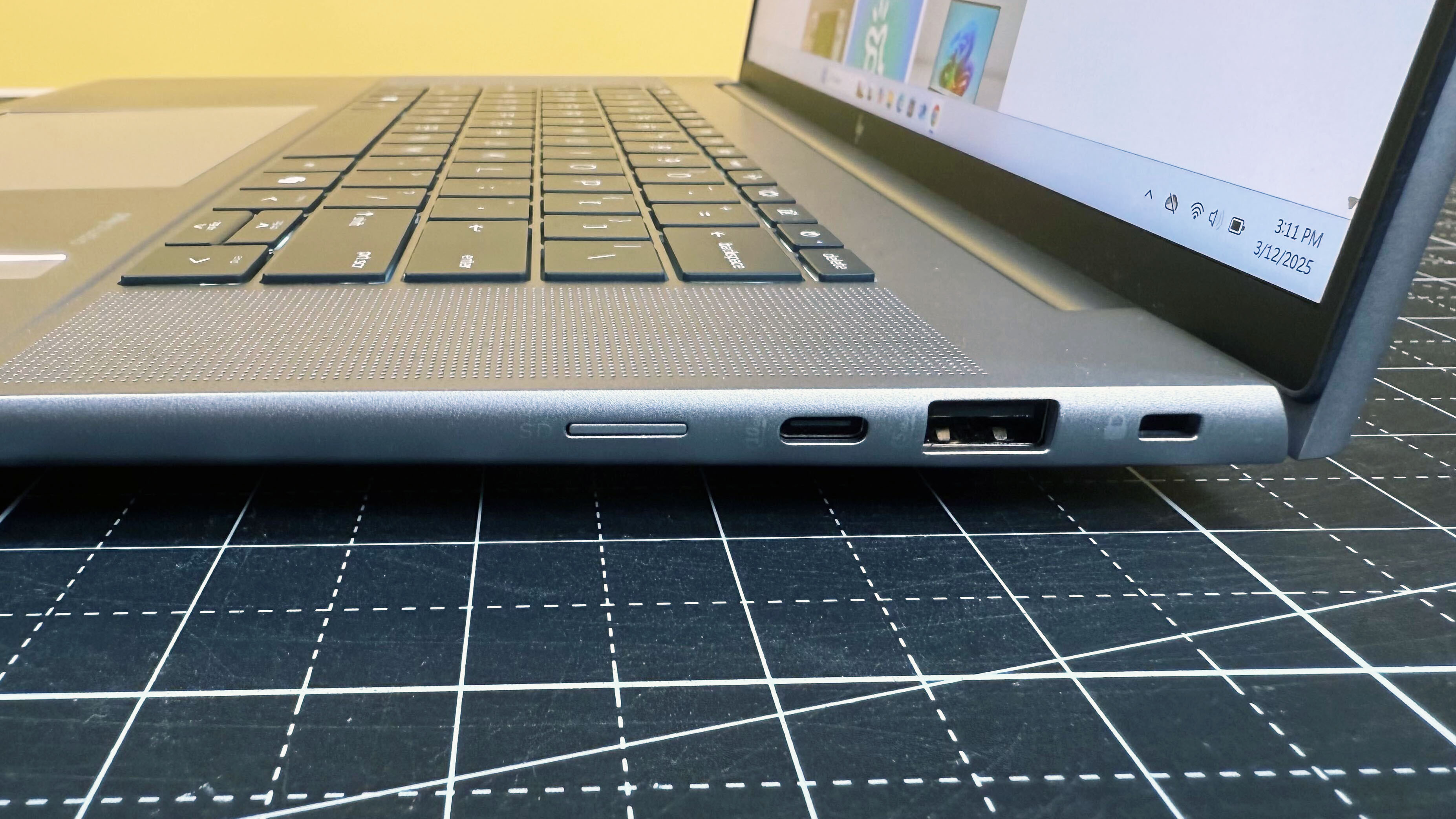 Close up of the right-side ports on the HP ZBook Studio 16 G11 mobile workstation on a white desk with a black table mat, against a yellow backdrop.