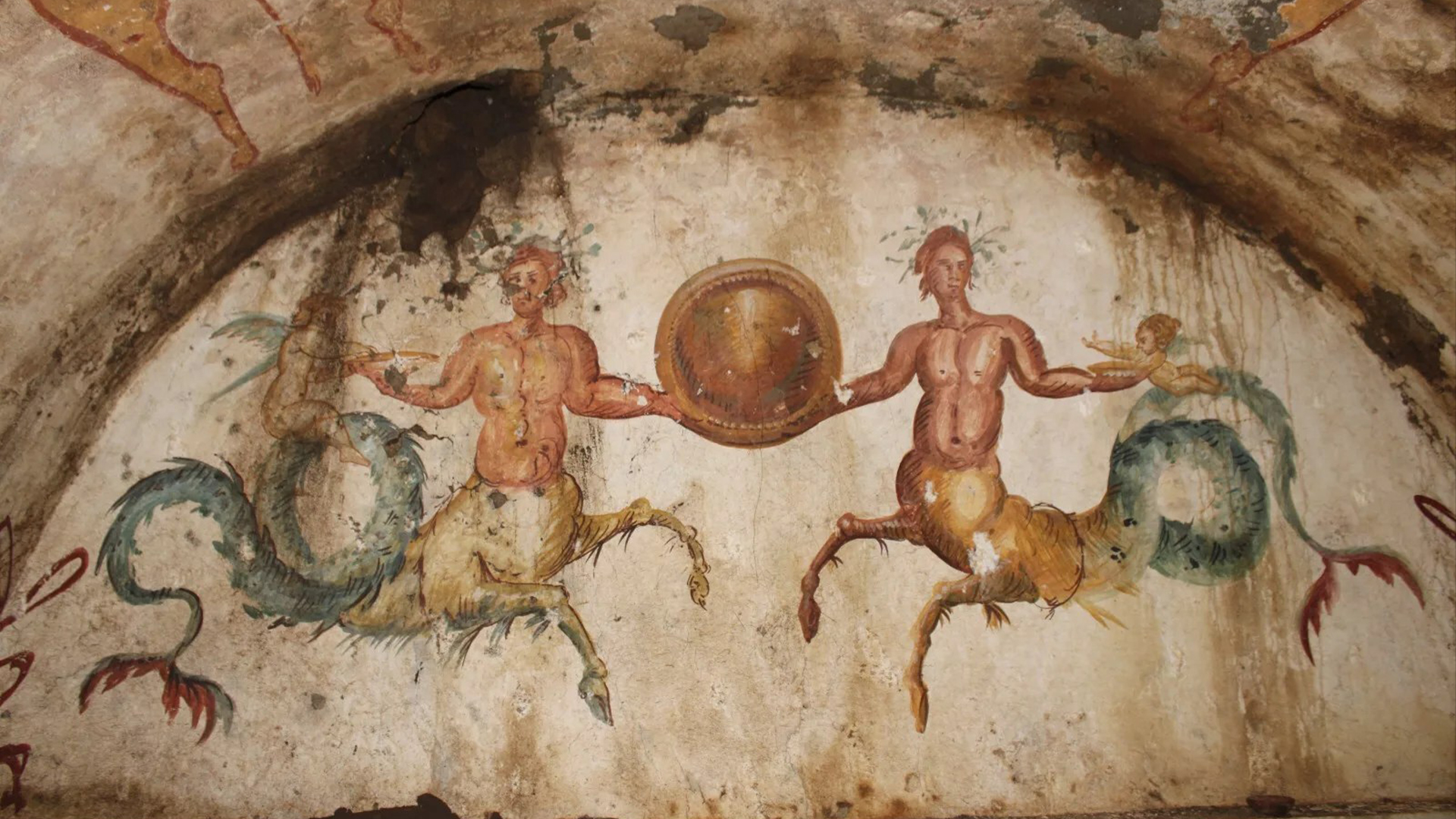 The tomb includes a painting of two ichthyocentaurs, or sea-centaurs, holding a circular shield next to two Cupid-like babies.