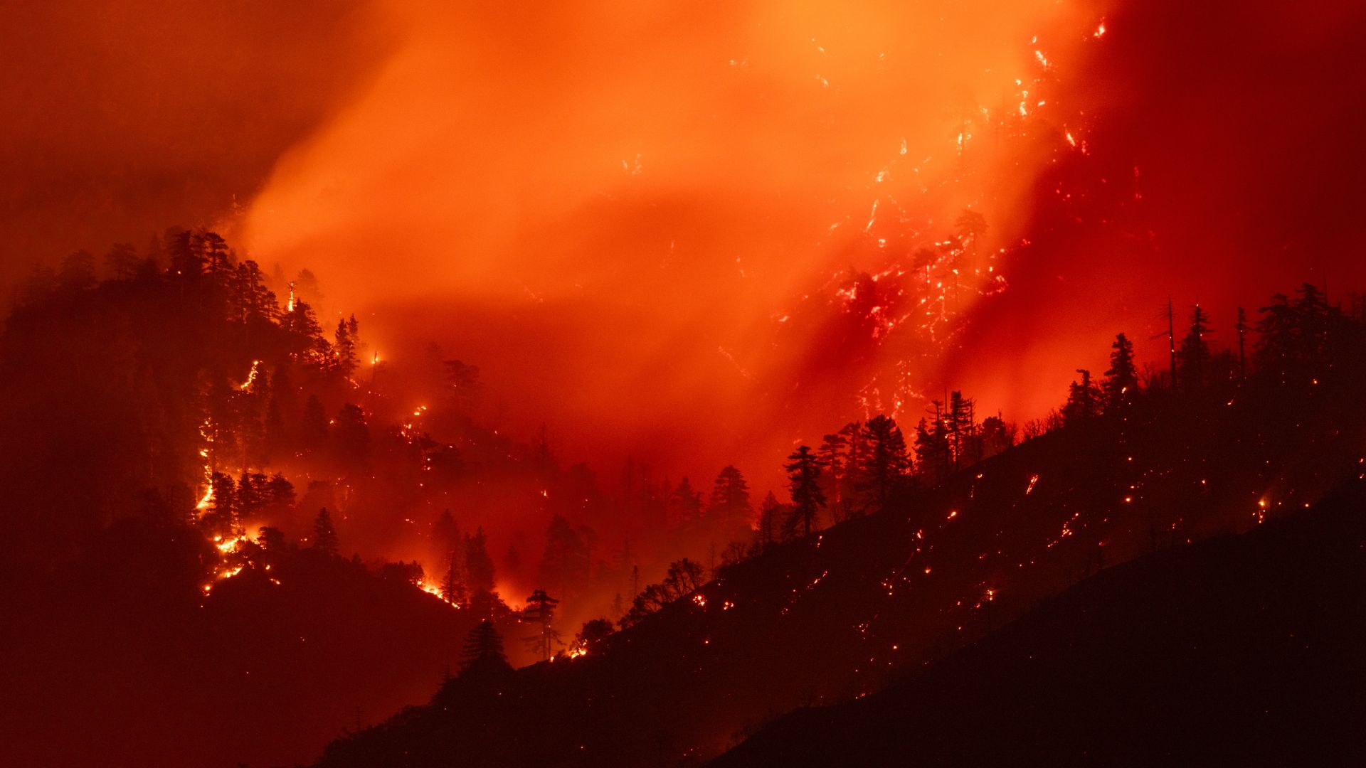 A landscape photo of forests in a mountainous area burning