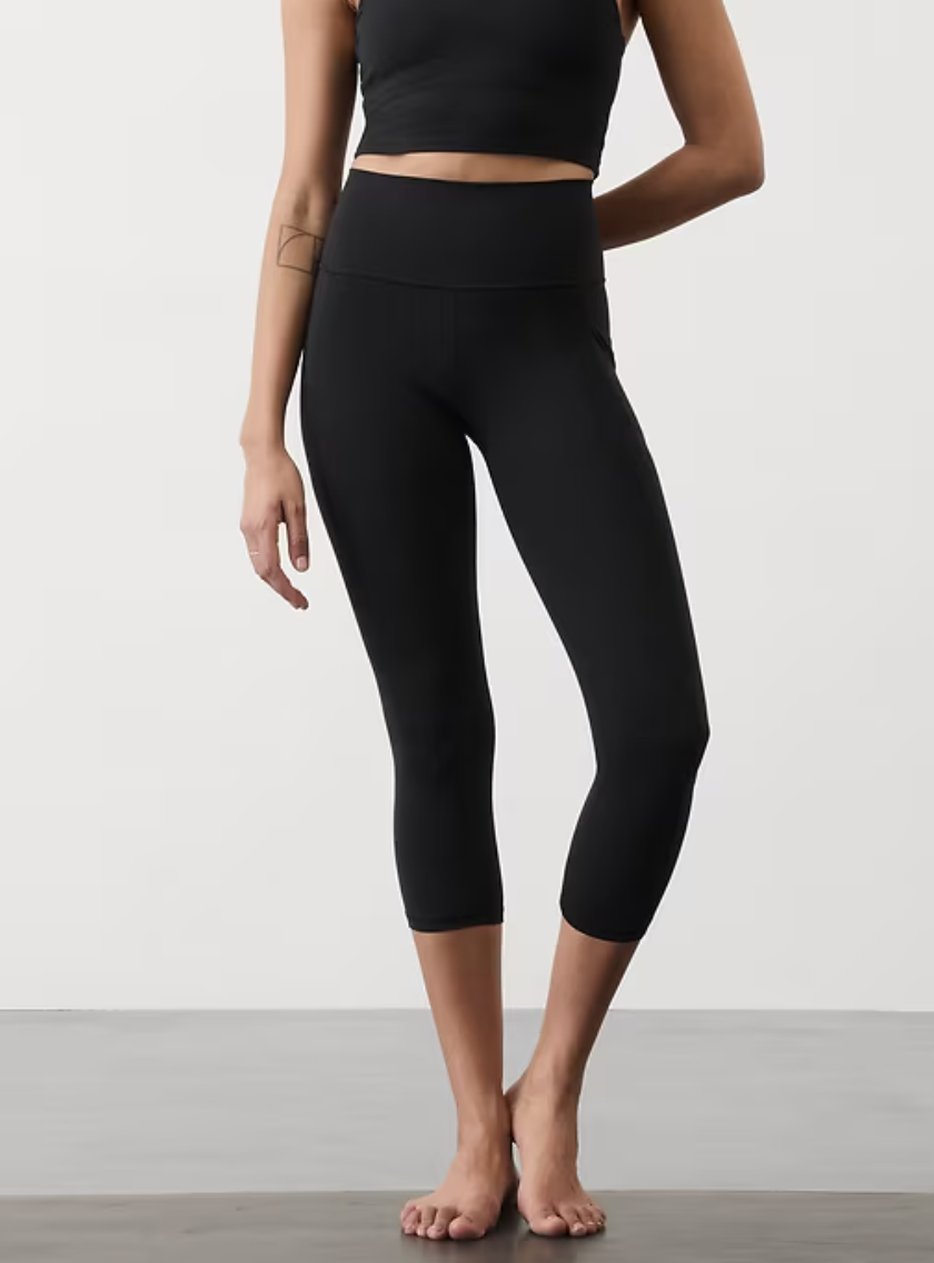 a model wearing a pair of high rise black capri leggings