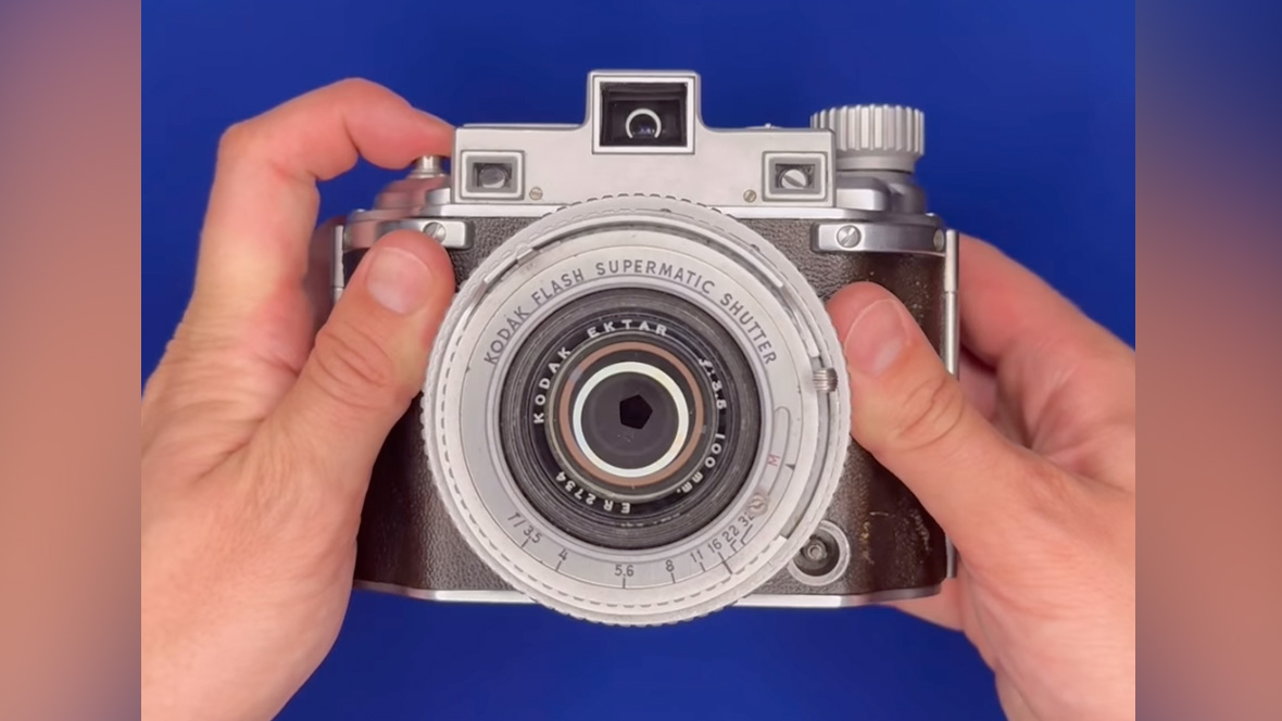 A Kodak Medalist II being handled on a blue background