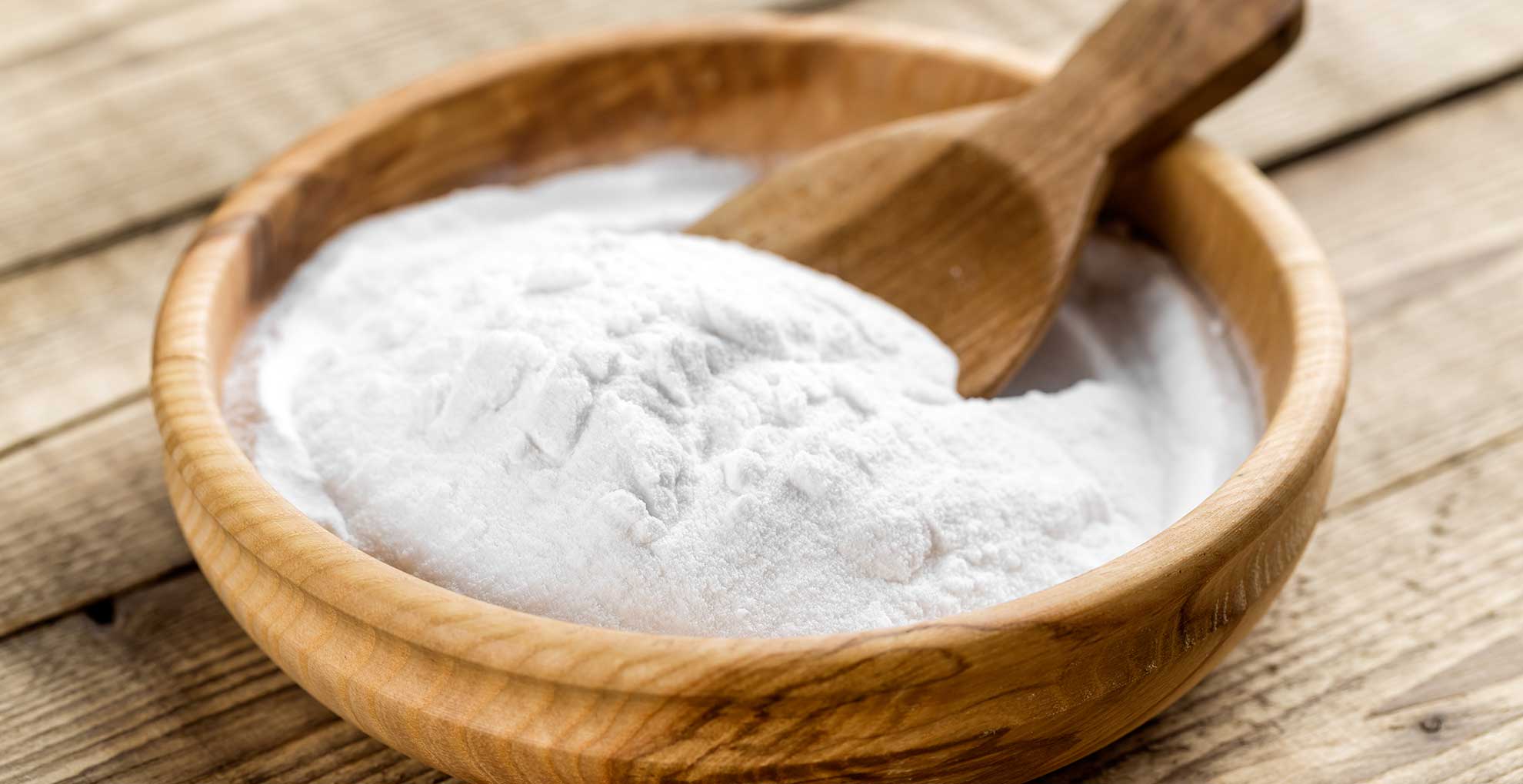 Wooden bowl of baking soda on a kitchen countertop to suggest how to. make a kitchen smell good