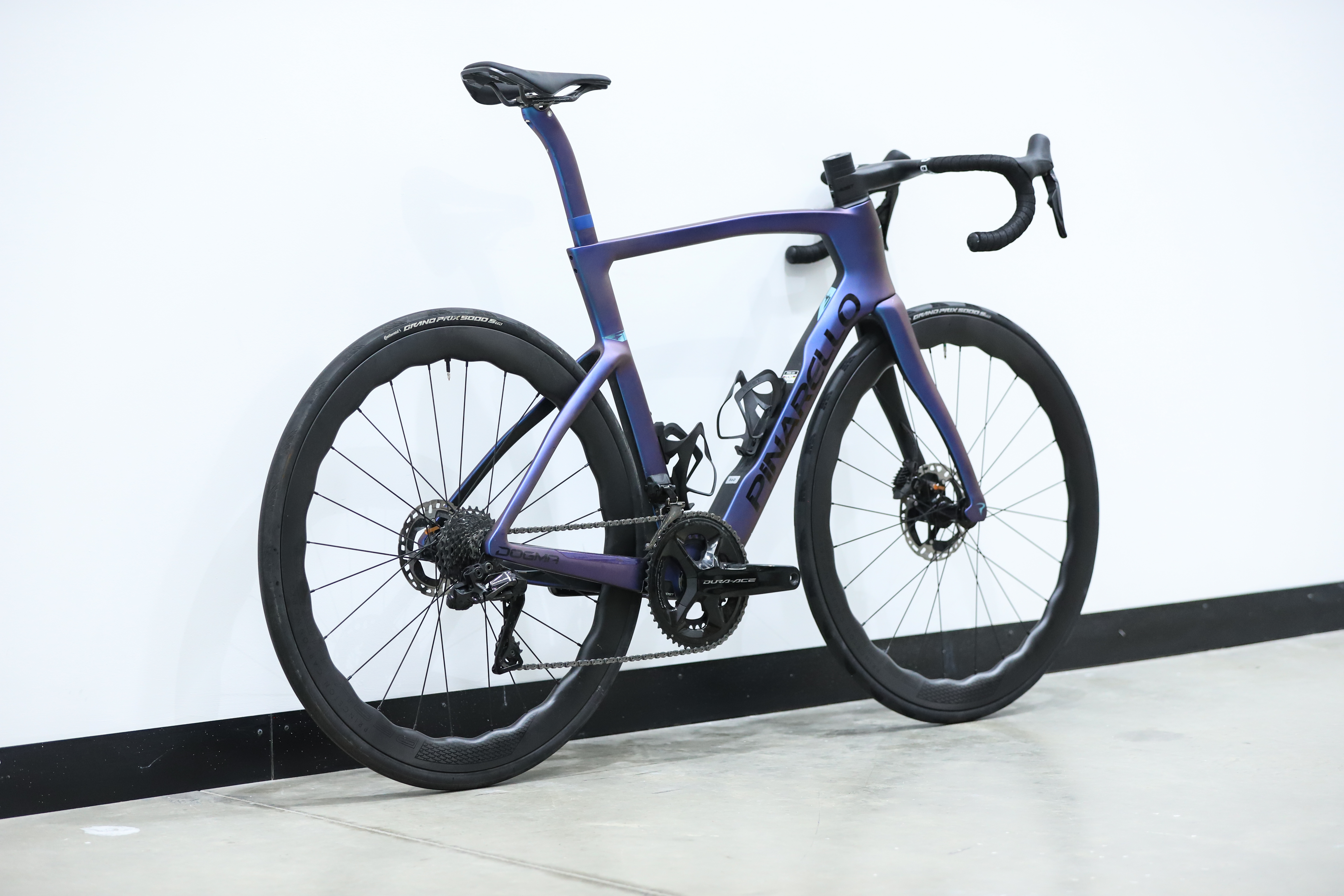 A blue pinarello dogma f stands against a white wall
