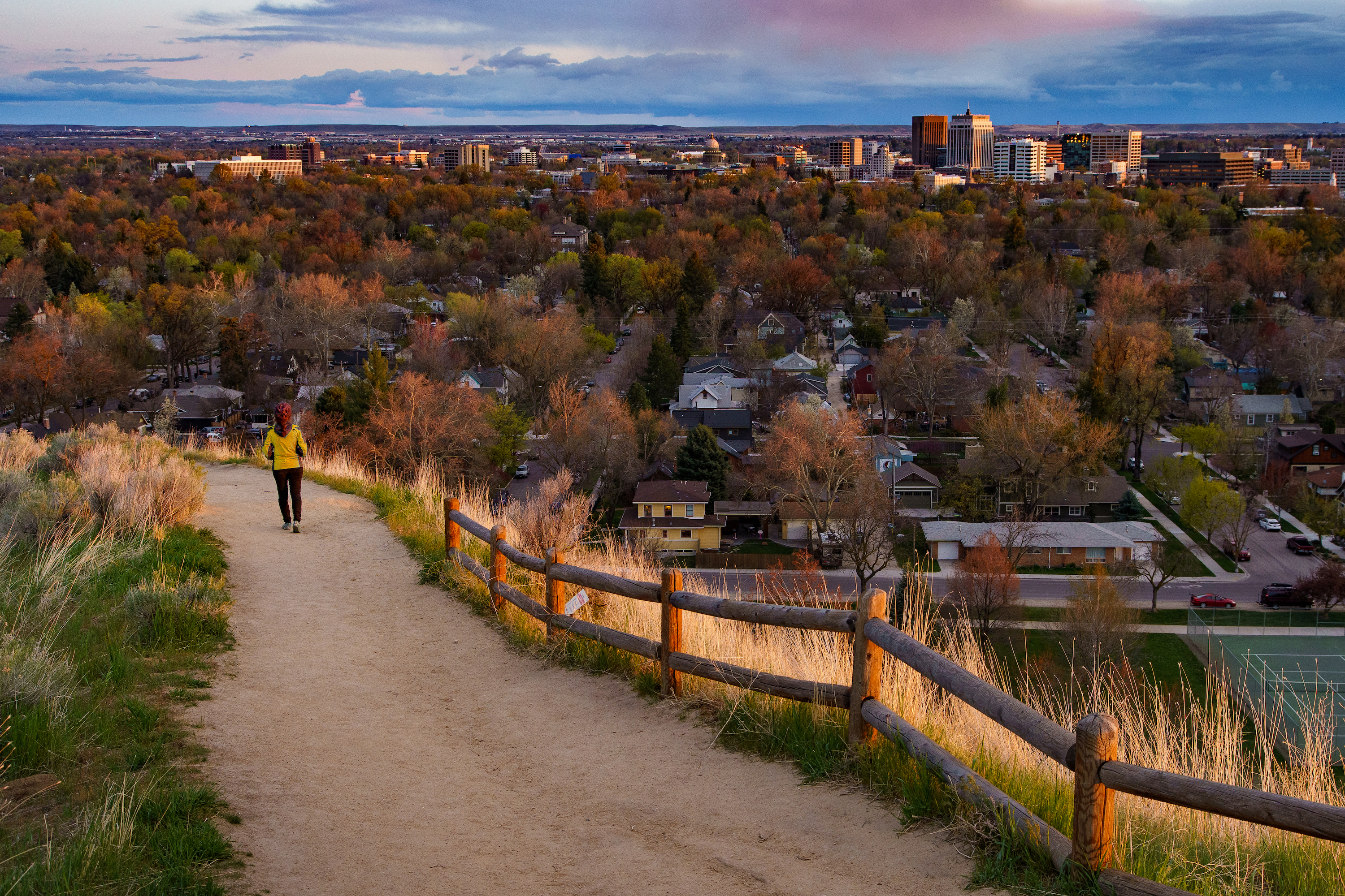A woman walks on a path with downtown Boise in the background