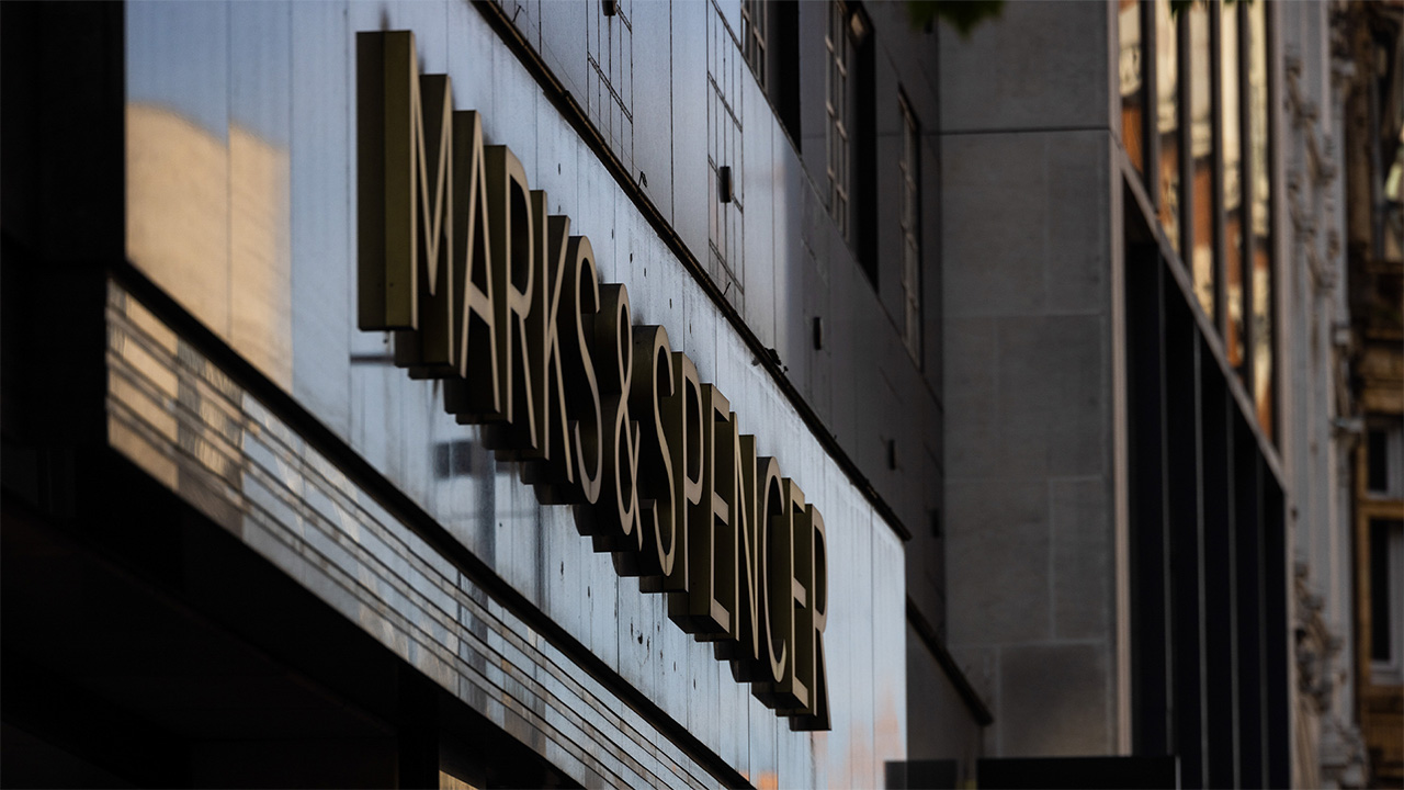 Shop front and sign of UK retailer M&S on low lit high street