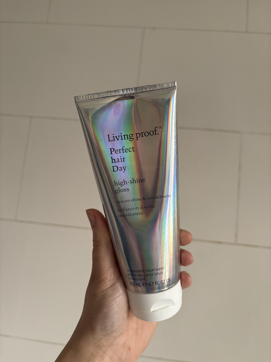 Mica Ricketts holding bottle of Living Proof Perfect Hair Day High-Shine Gloss