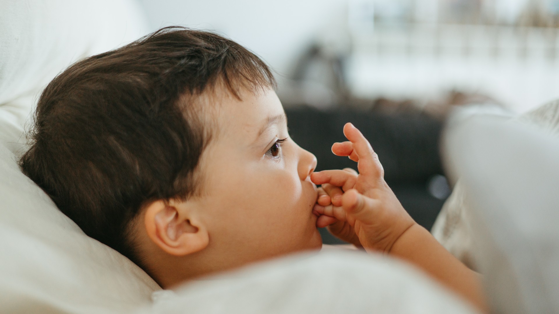 A close-up picture of a little boy biting her nails. 