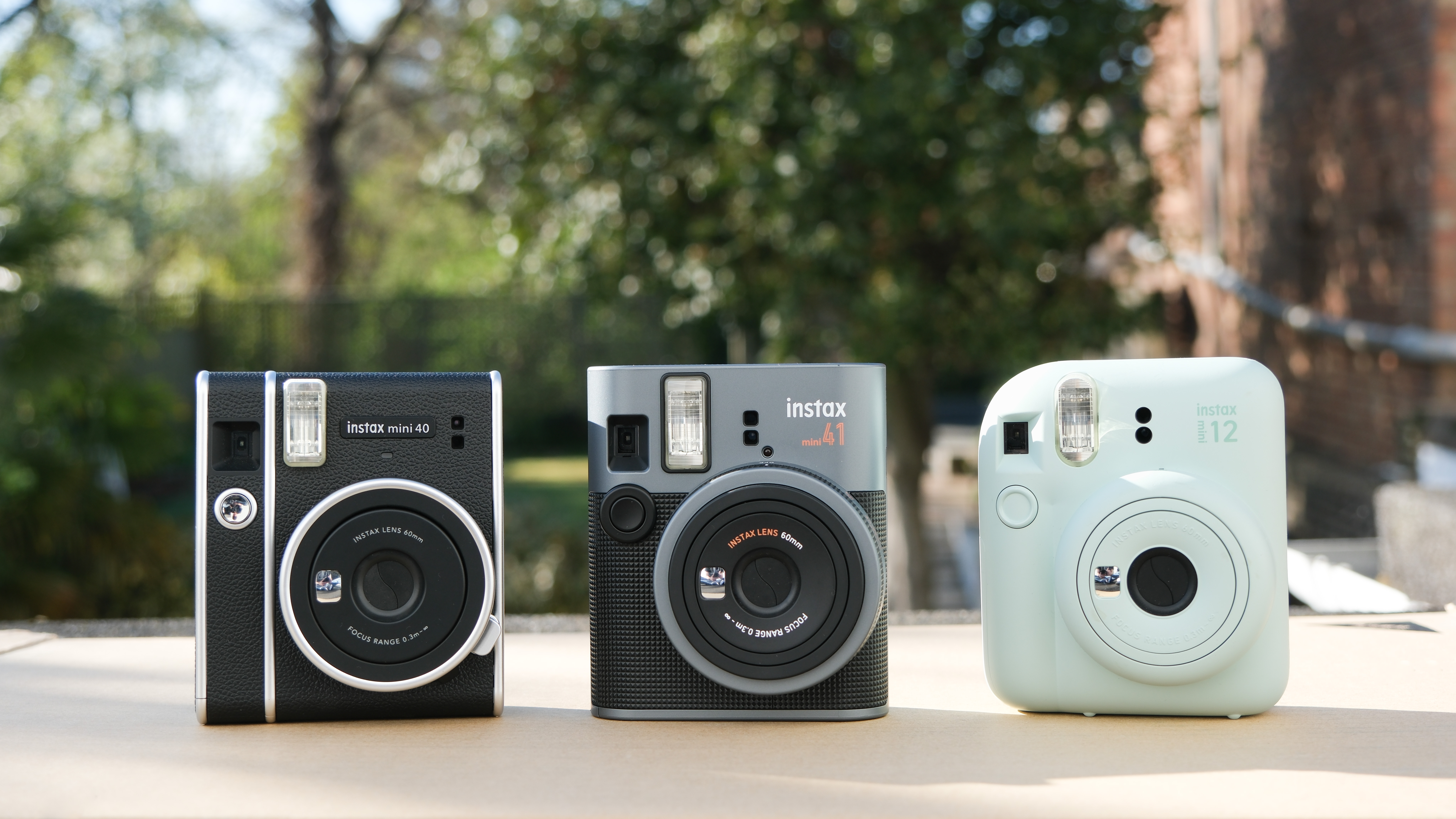 Fujifilm Instax Mini 41 camera next to Fujifilm Instax Mini 40 and Fujifilm Instax Mini 12 cameras
