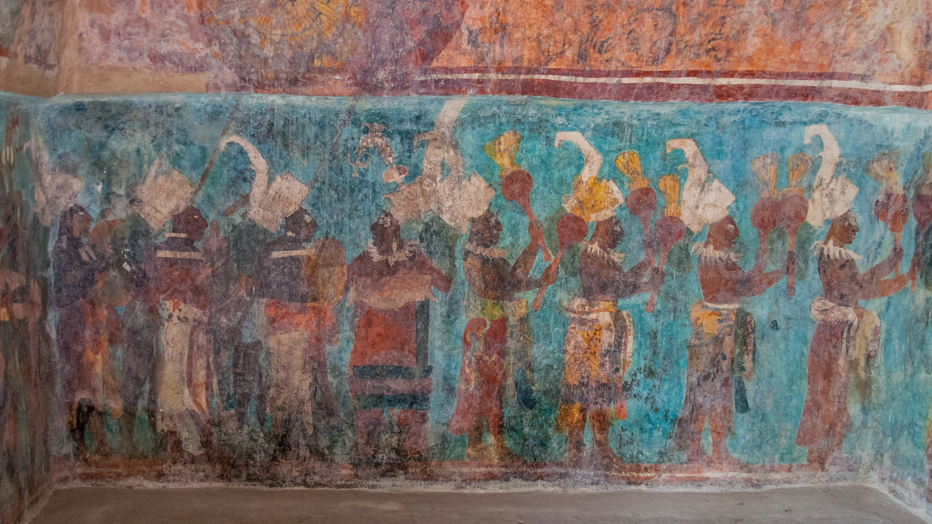 Close-up of a wall mural with dark-skinned people facing right, dressed in fancy outfits; the background is a stunning turquoise color called Maya blue