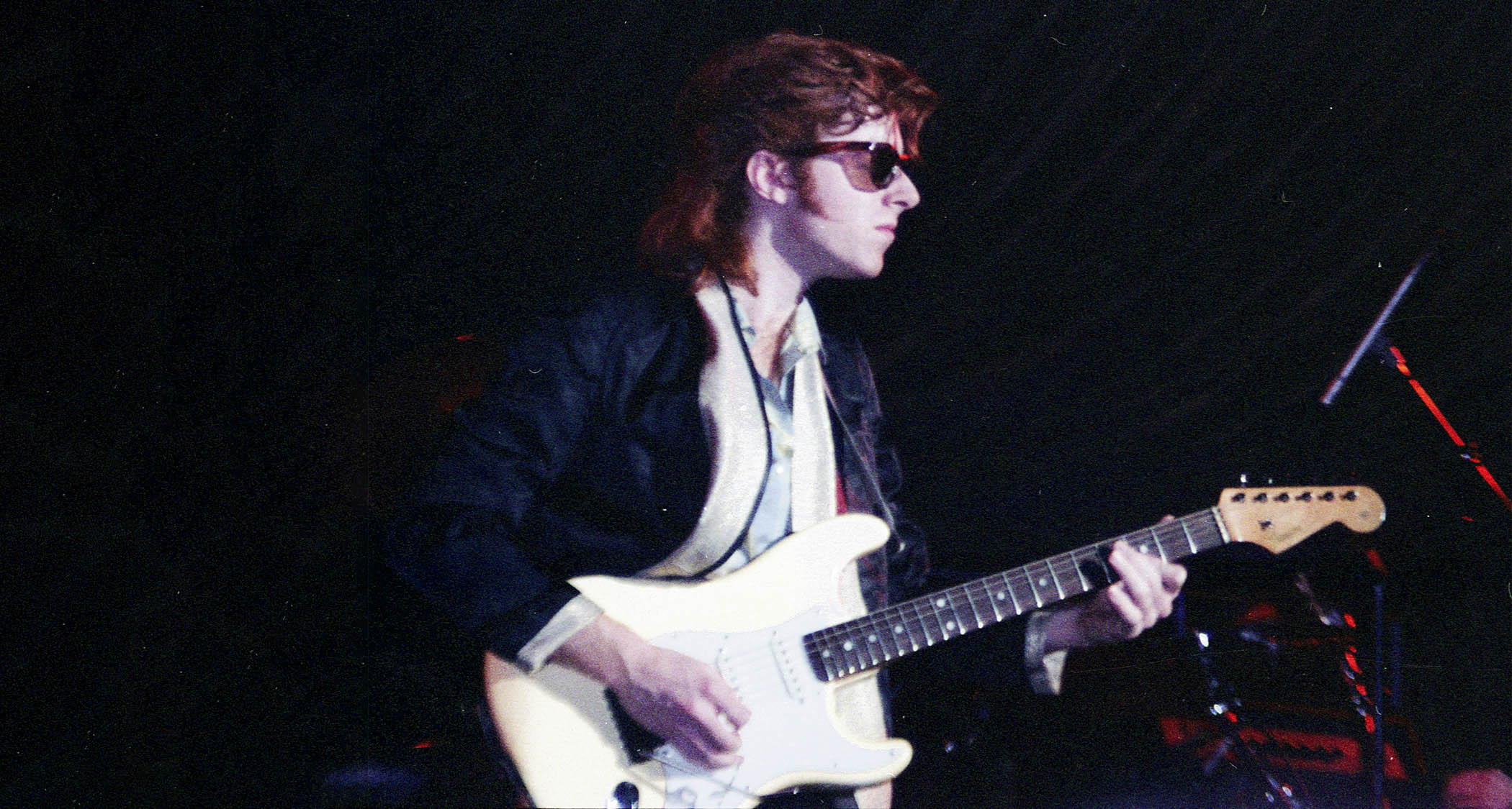 John McCurry performs in the &#039;80s with dark wayfarer sunglasses and an Olympic White Stratocaster.