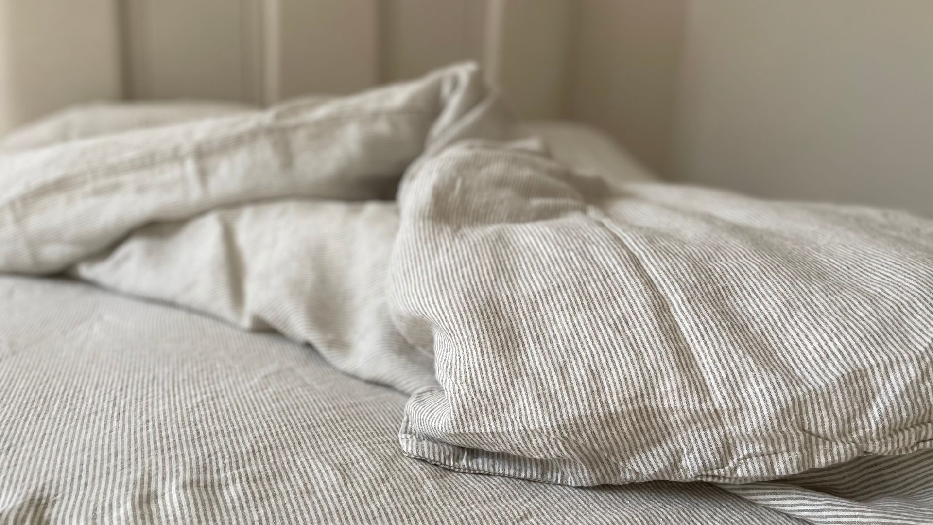 Secret Linen Store Natural Sid Stripe Linen on an unmade duvet