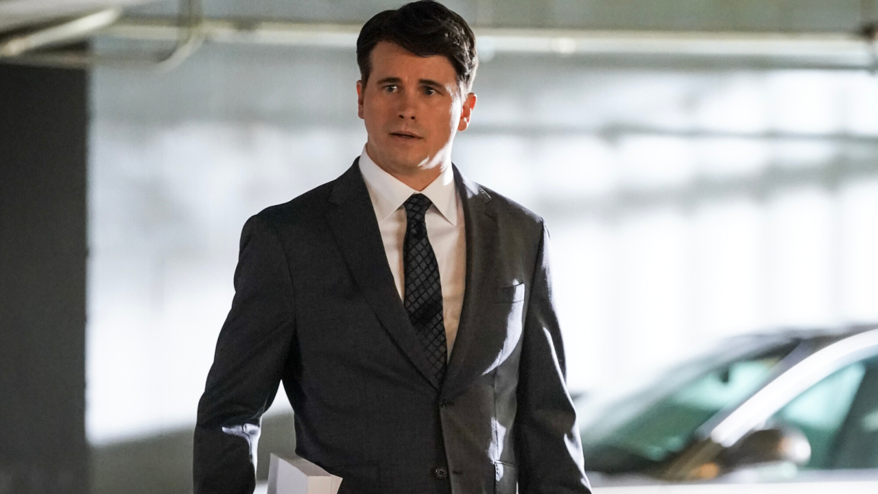 Jason Ritter walks through a parking garage with a huge file in his hand in Matlock S1 E14 - &quot;Game Day.&quot;
