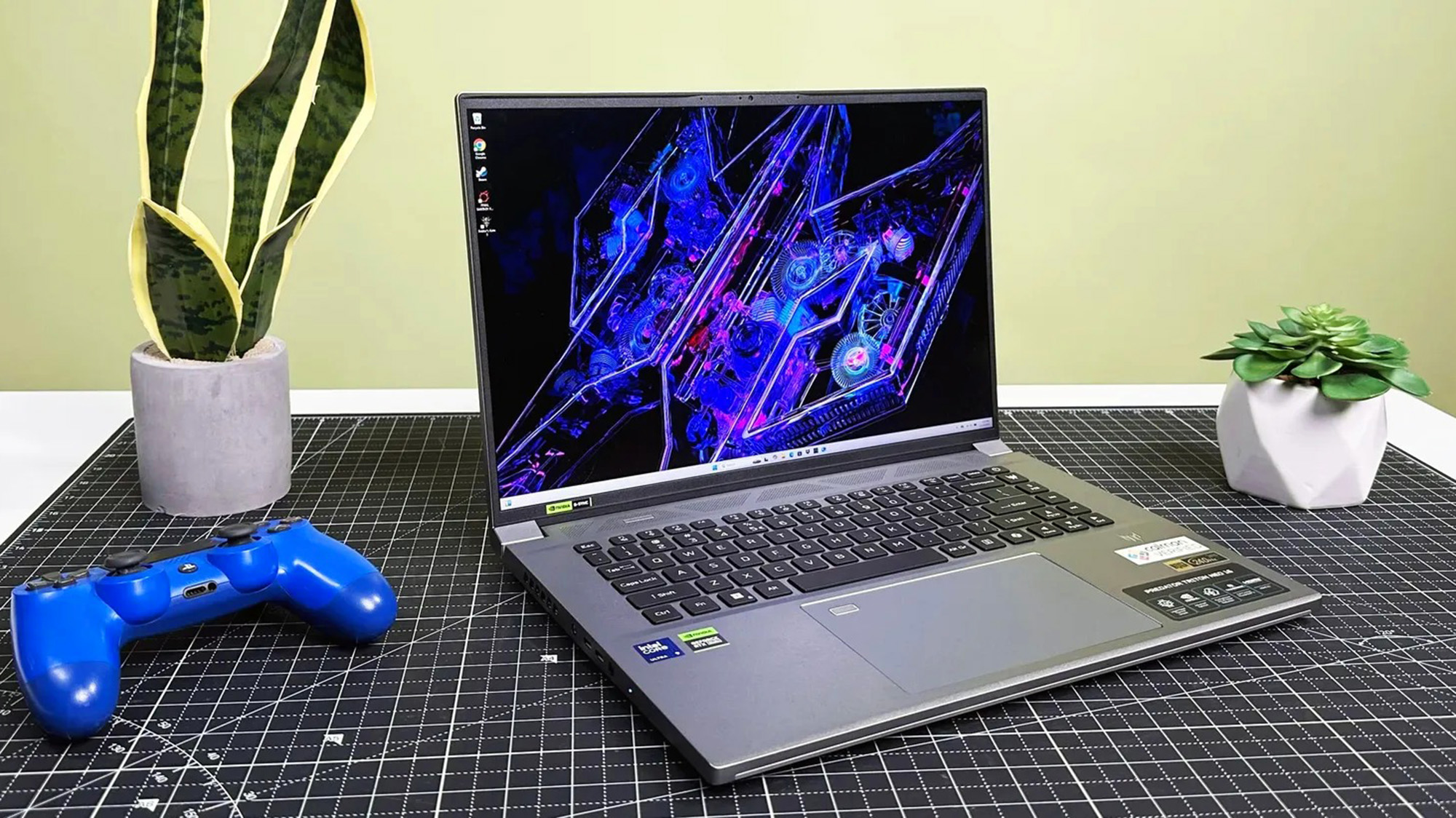 Acer Predator Triton Neo 16 open on a grid mat, with two plants and a gaming controller sitting nearby.