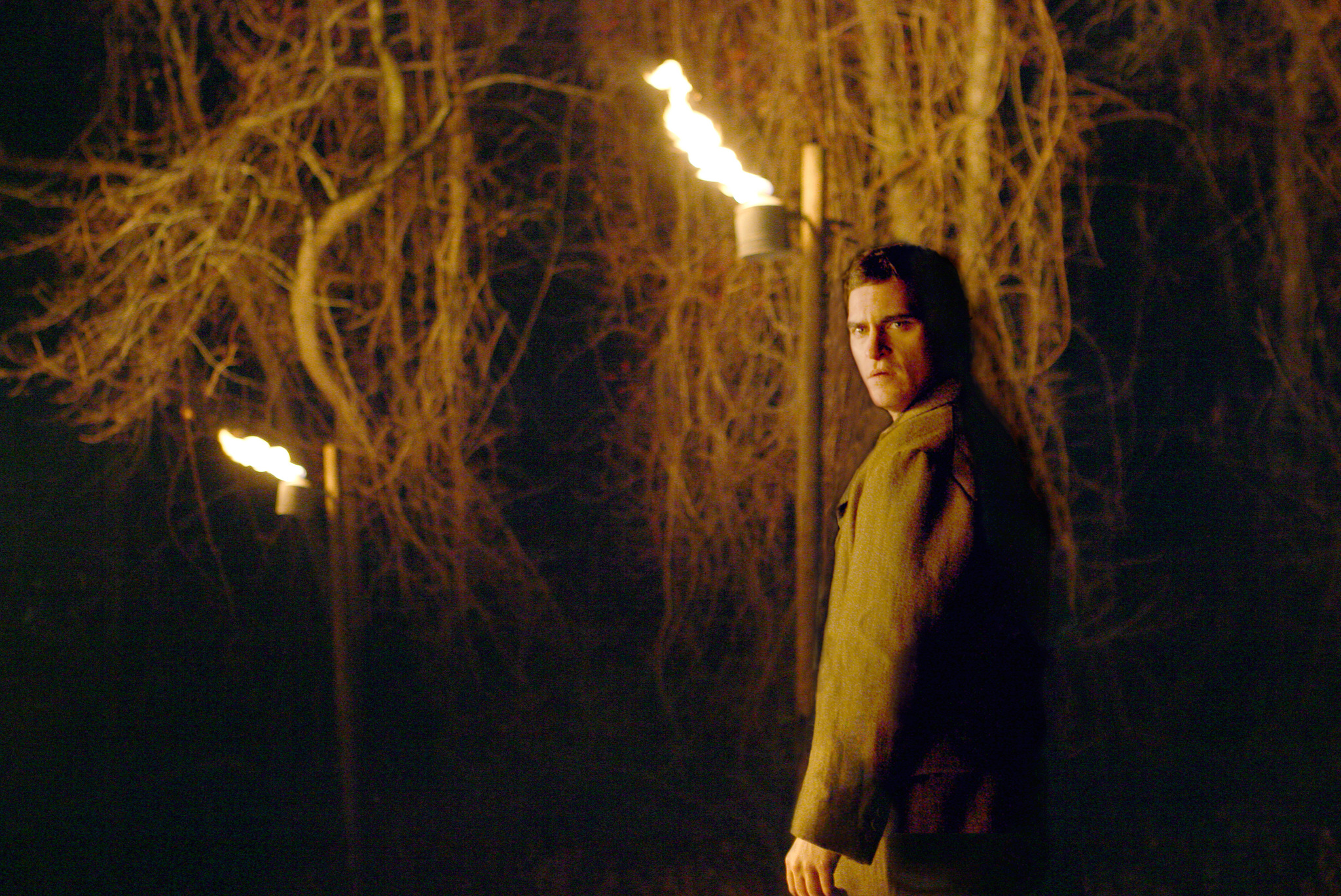Joaquin Phoenix walks through a wooded area with a lit torch in 'The Village'