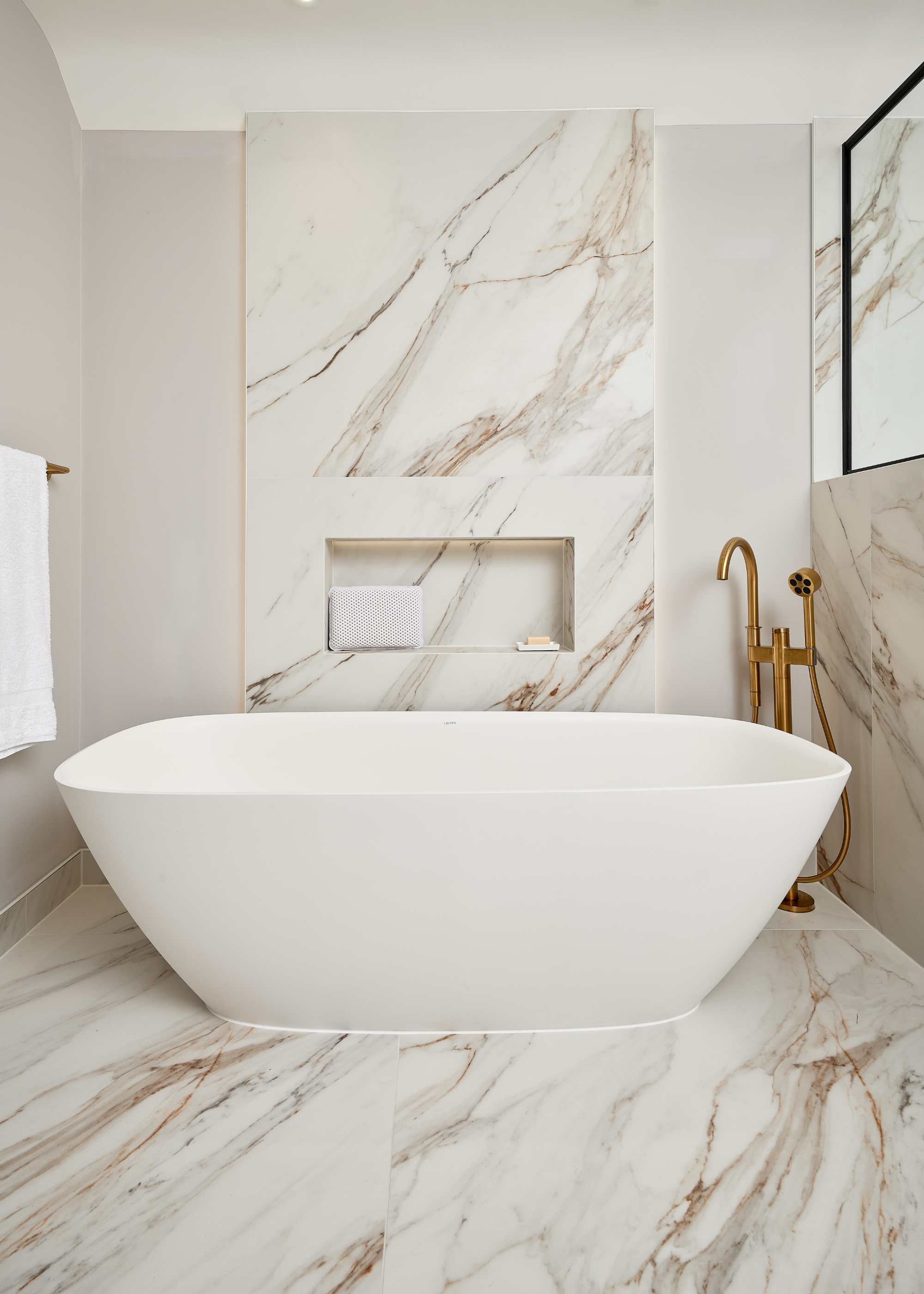 freestanding tub in a marble clad bathroom