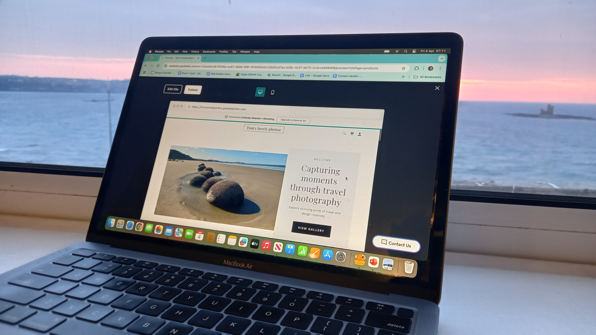 Laptop next to window overlooking the sea, featuring website being edited in GoDaddy interface