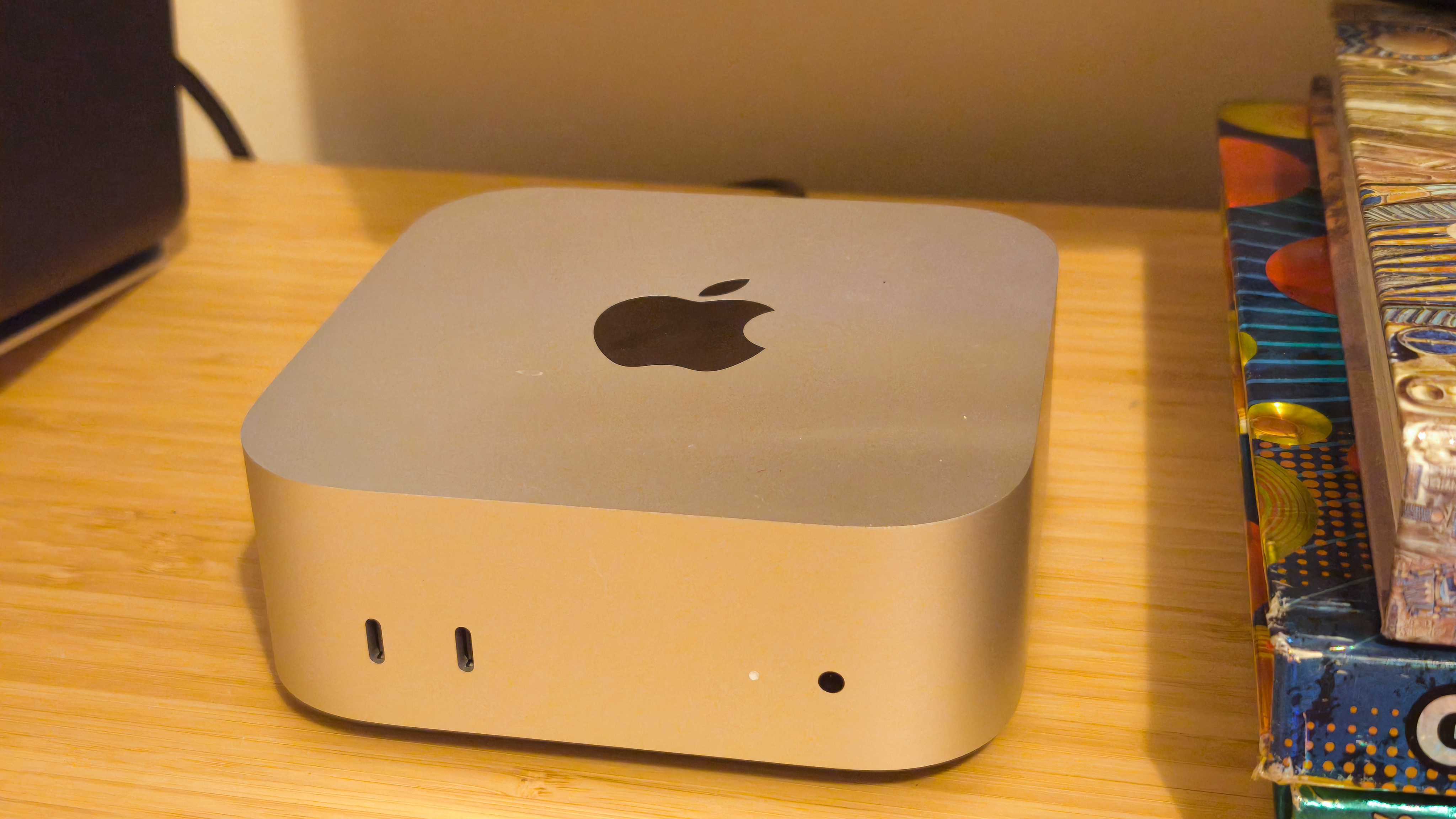 A silver Apple Mac mini (M4) on a wooden desk
