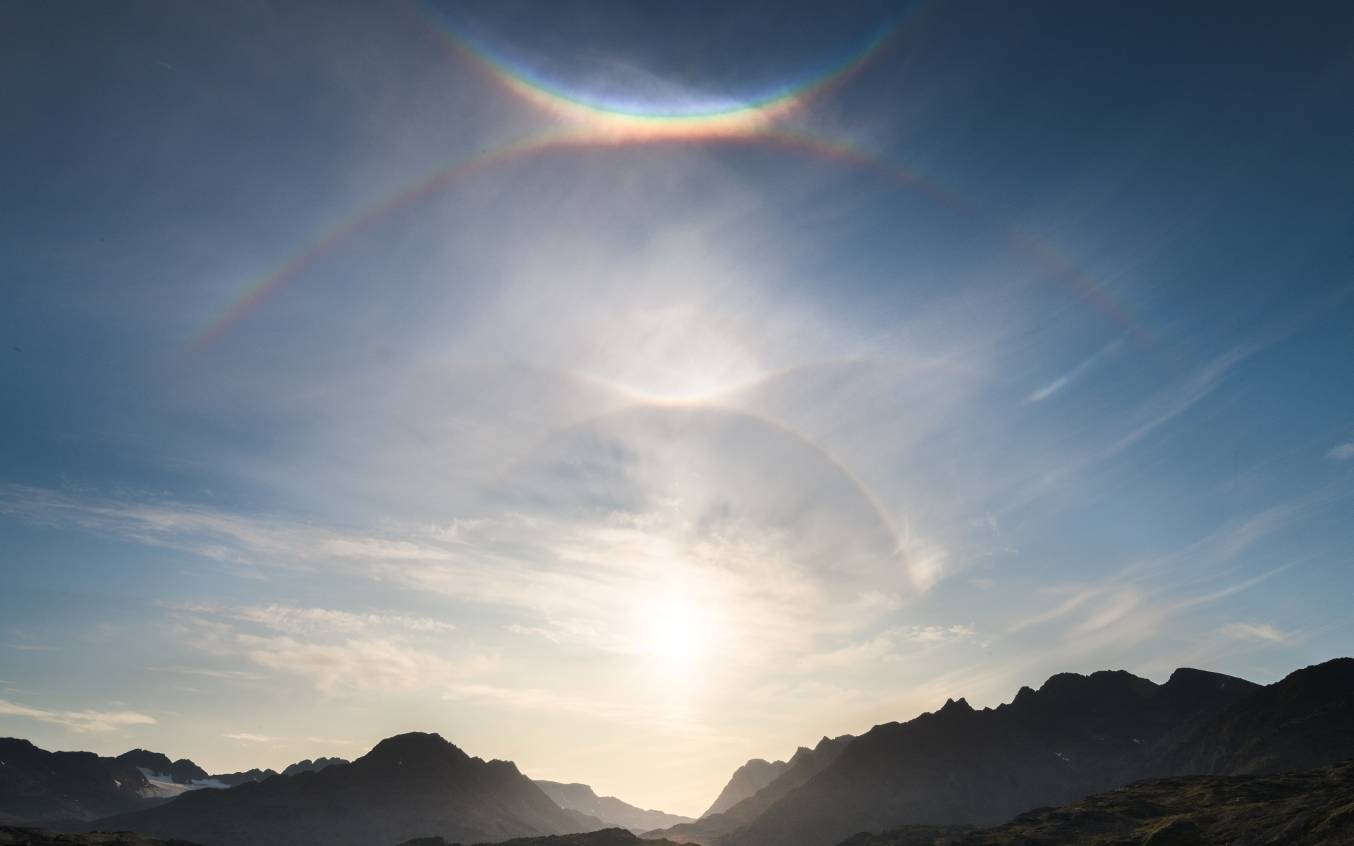 two distinct arcs of light surround the sun.