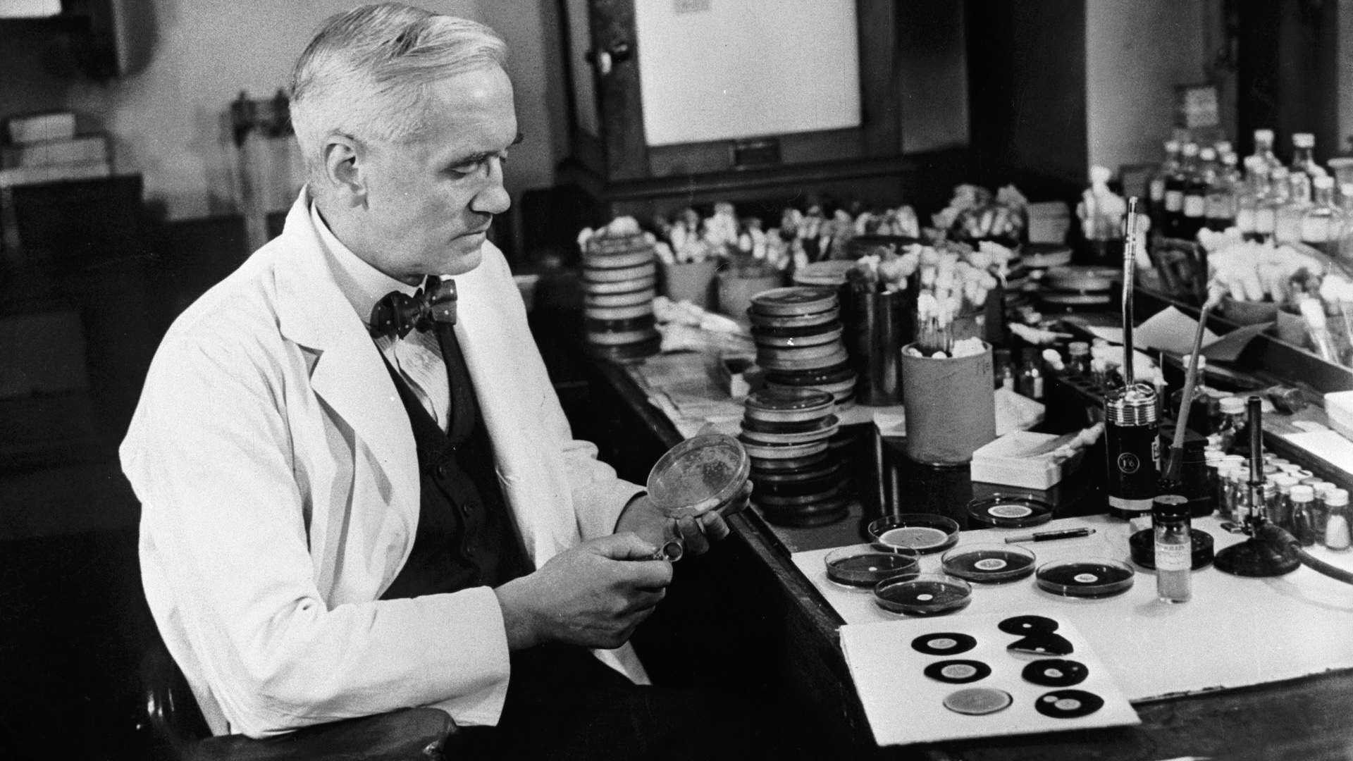 a black and white photograph of Alexander Fleming in his laboratory