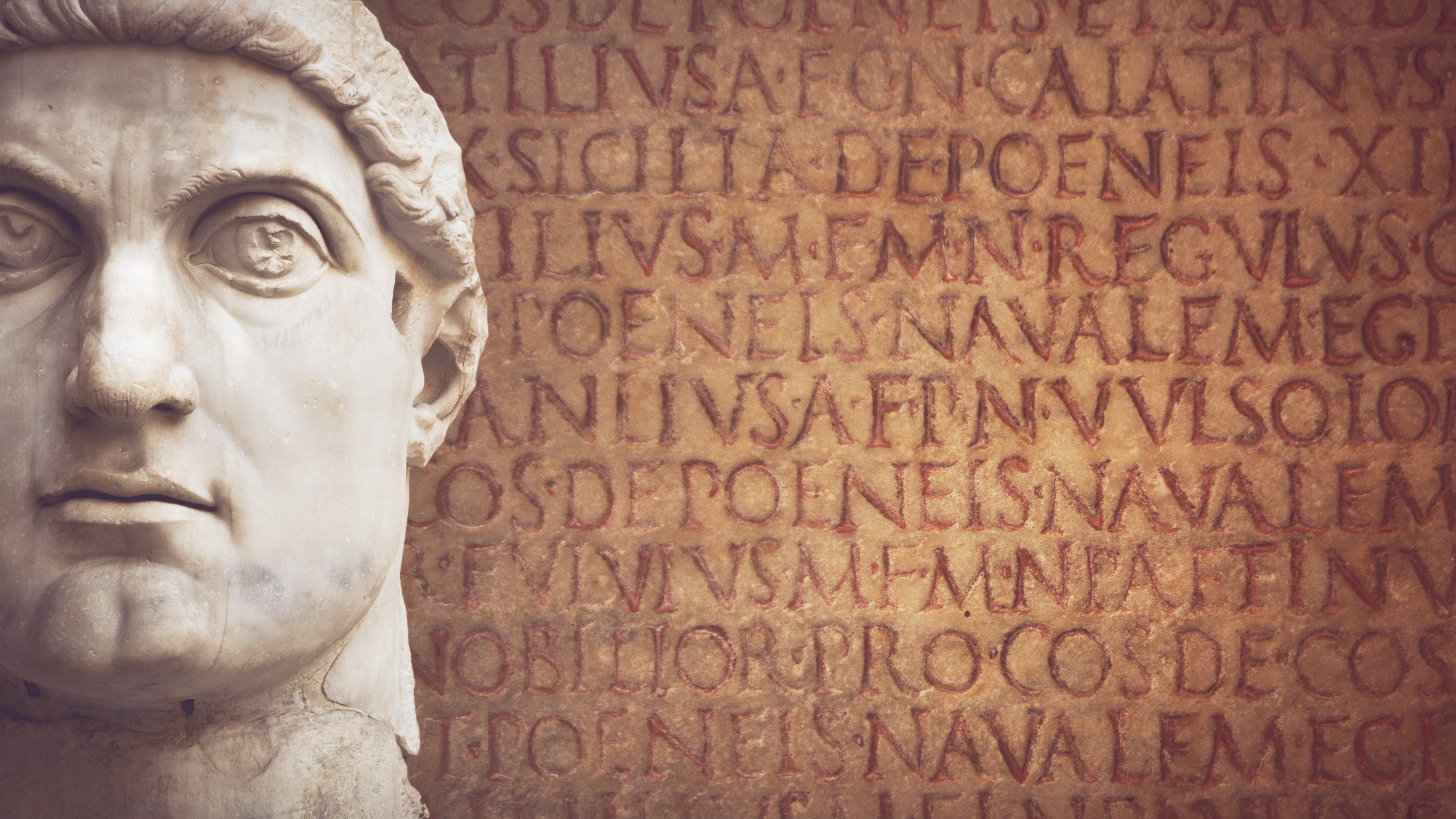 marble statue of roman emperor constantine's face on background of roman writing