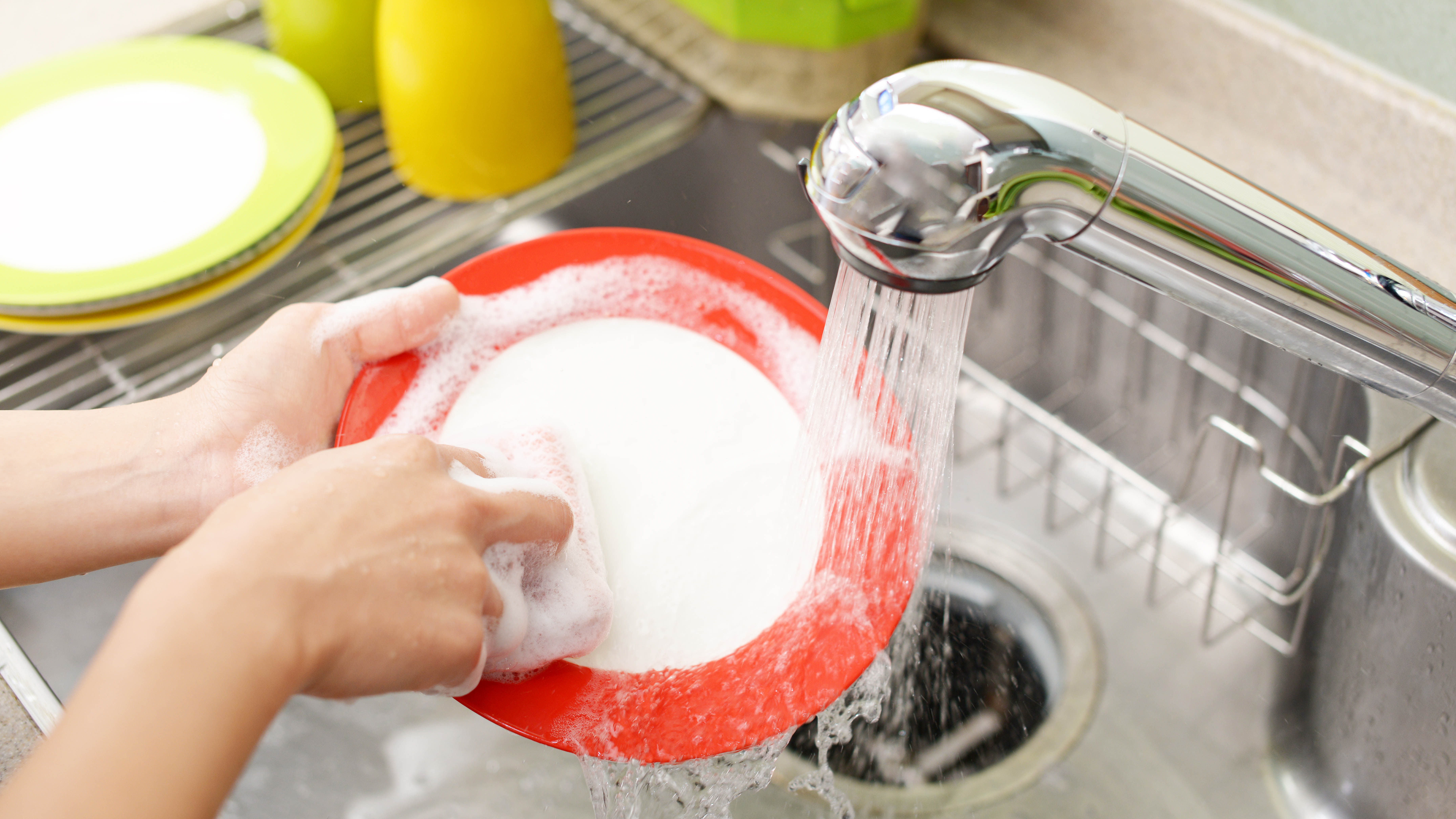 Someone washing a plate by hand in a sink with soap
