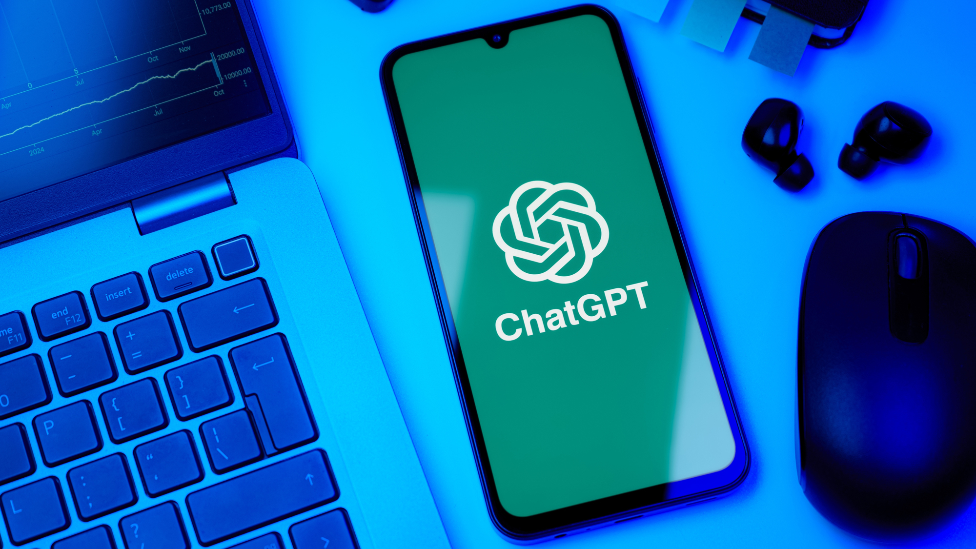 ChatGPT logo on smartphone next to a laptop
