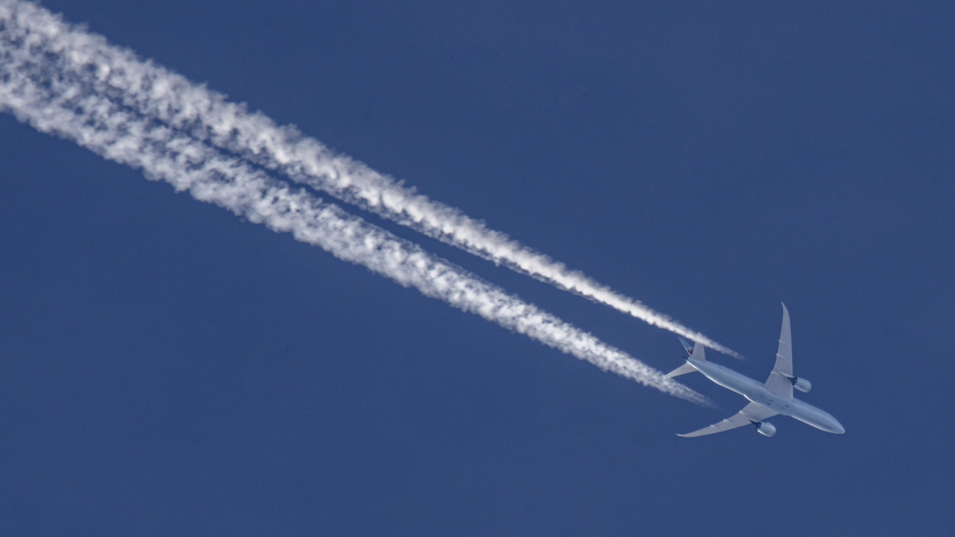 An aircraft releases trails of condensation behind it