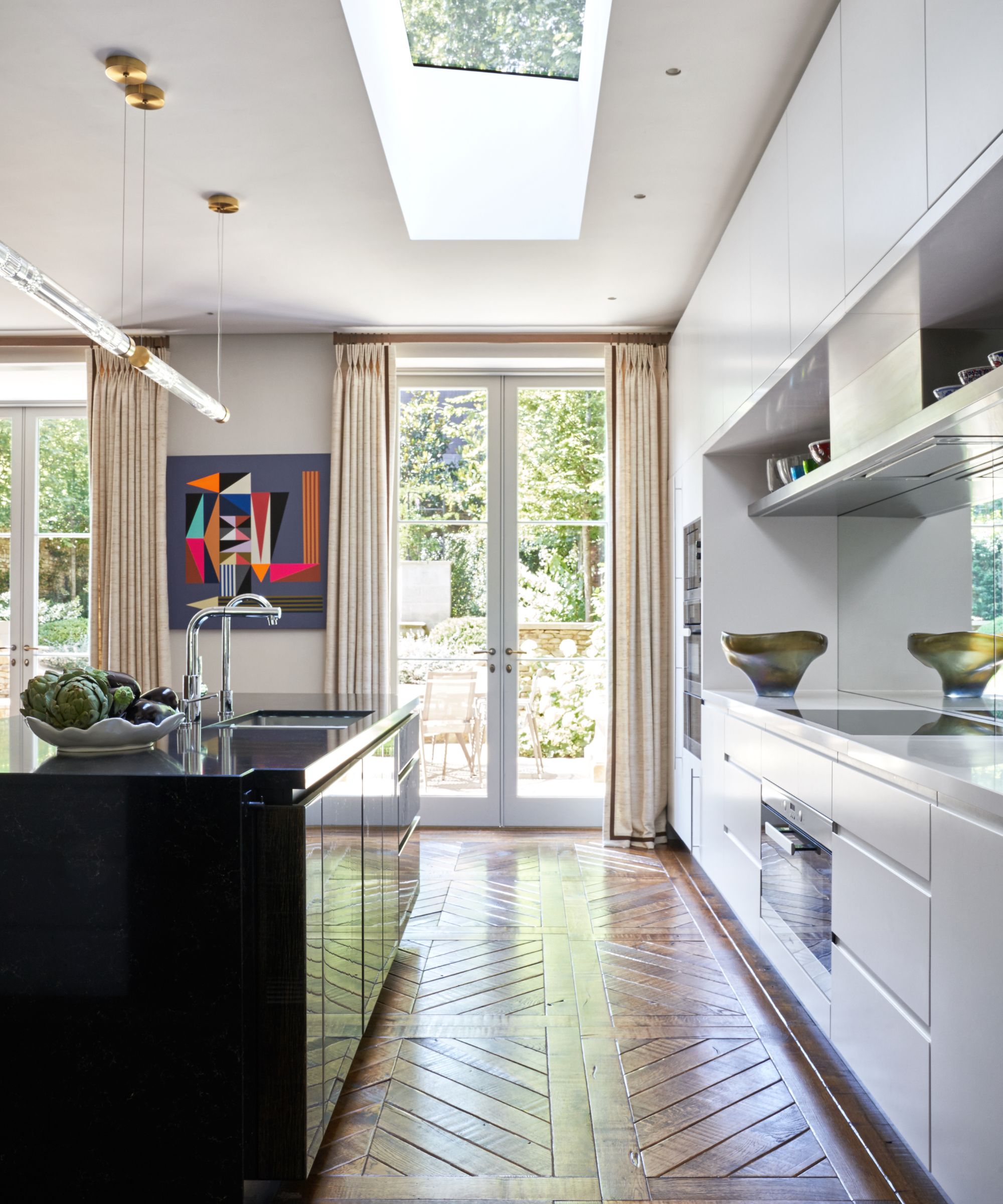 A black kitchen island pairs with white wall cabinetry in this modern kitchen