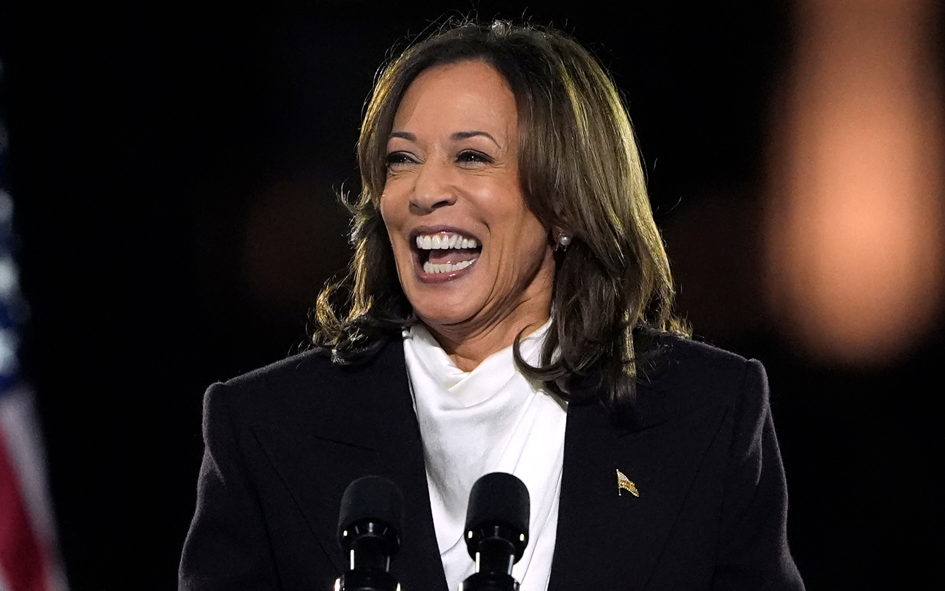 Kamala Harris speaking in Washington DC wearing a white top with a gold flag pin