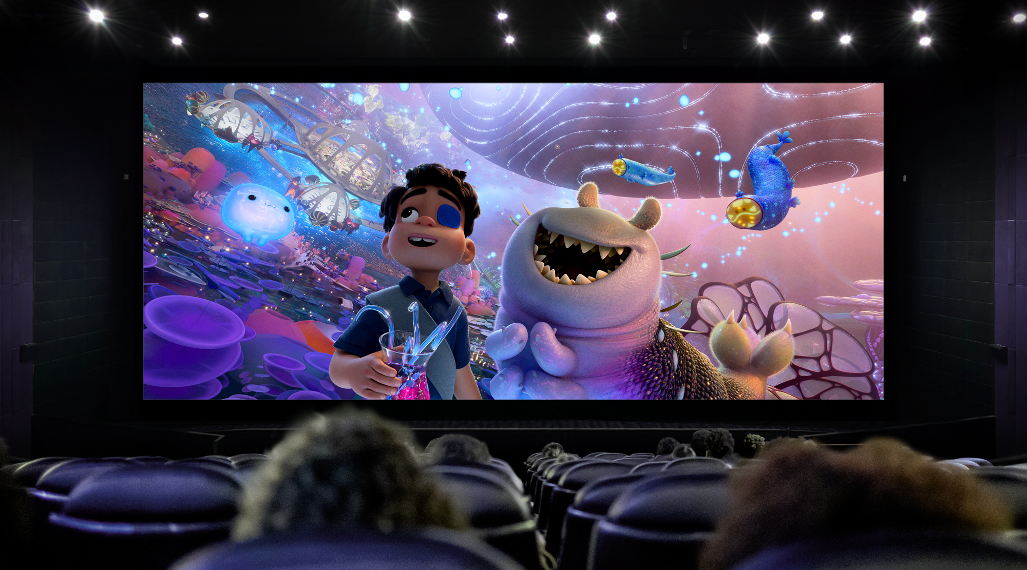 A cinema screen with Pixar&#039;s upcoming animated feature, Elio, on screen watched by a seated crowd.