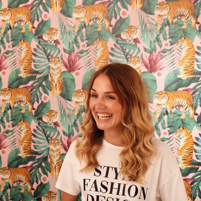 Chelsea Clark, head of marketing for I Love Marketing, in front of a wall covered in pink, leaf and tiger wallpaper
