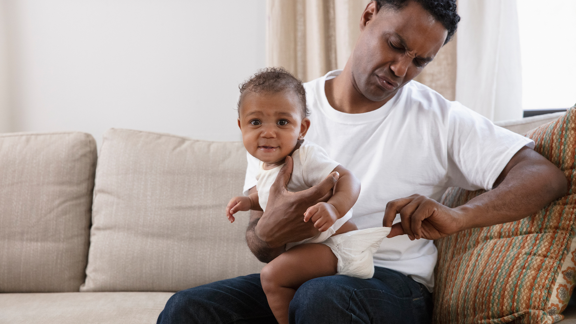 Father holding baby with dirty diaper.