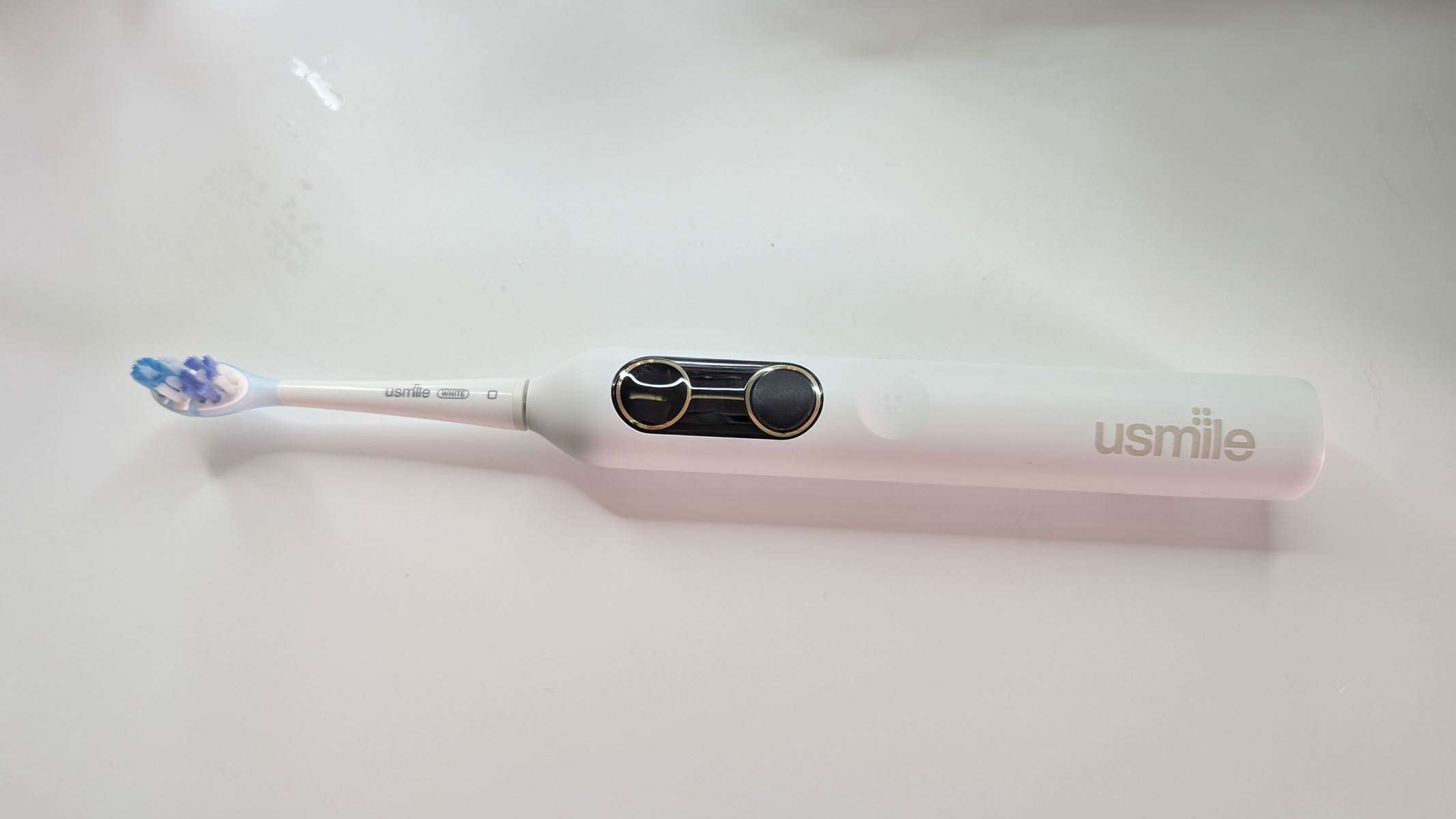 usmile Y10 PRO electric toothbrush laying flat on a white table